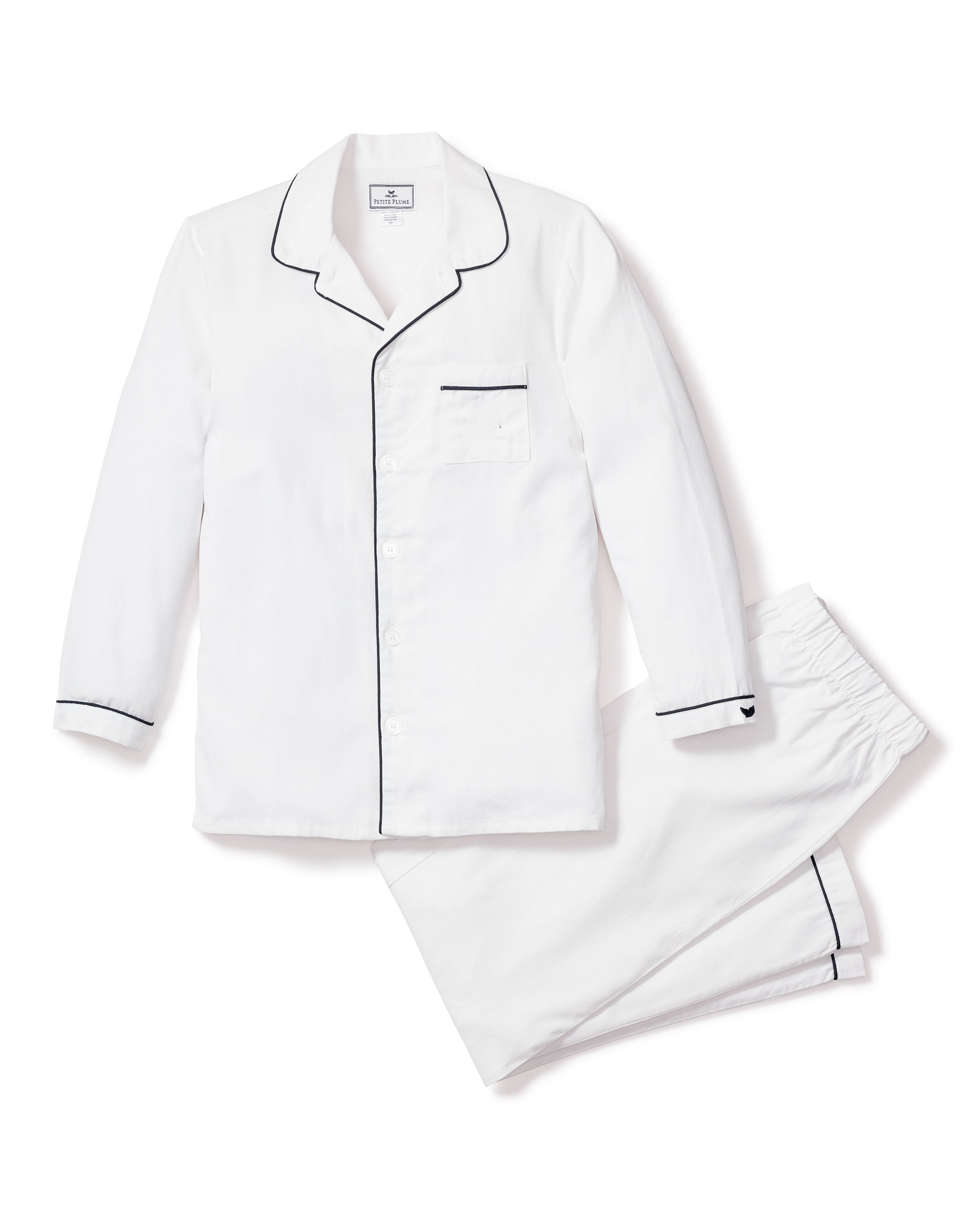 The Kids Twill Pajama Set in White with Navy Piping by Petite Plume includes a yarn-dyed cotton, long-sleeved, button-up top with a chest pocket and matching pants.