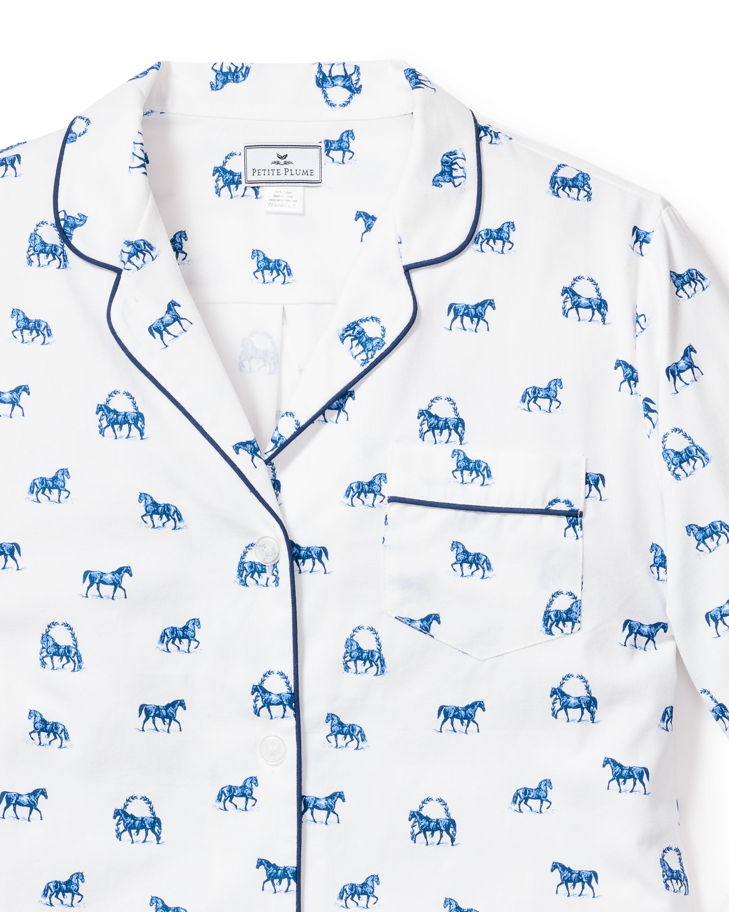 The Womens Twill Pajama Set in The Equestrian by Petite Plume features a white top with classic equestrian print and dark blue piping on the collar, button line, and pocket, crafted from the finest quality cotton for ultimate comfort and style.