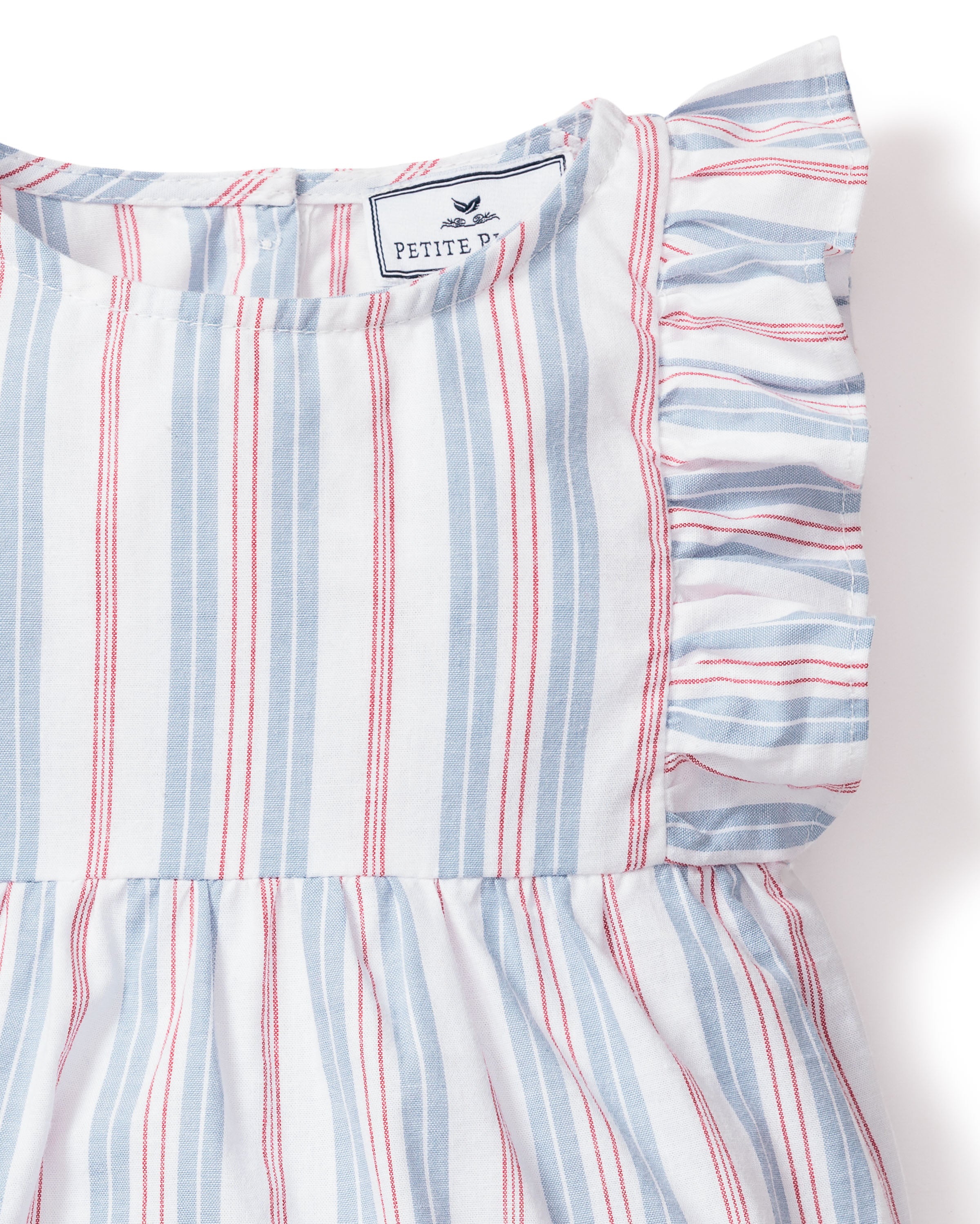 Close-up of Petite Plumes Babys Twill Ruffled Romper in Vintage French Stripes. It has vertical blue and red stripes on a white background, reminiscent of stripe pajamas, with ruffled shoulders, a visible bird logo tag, and a gathered waist for a flared look.