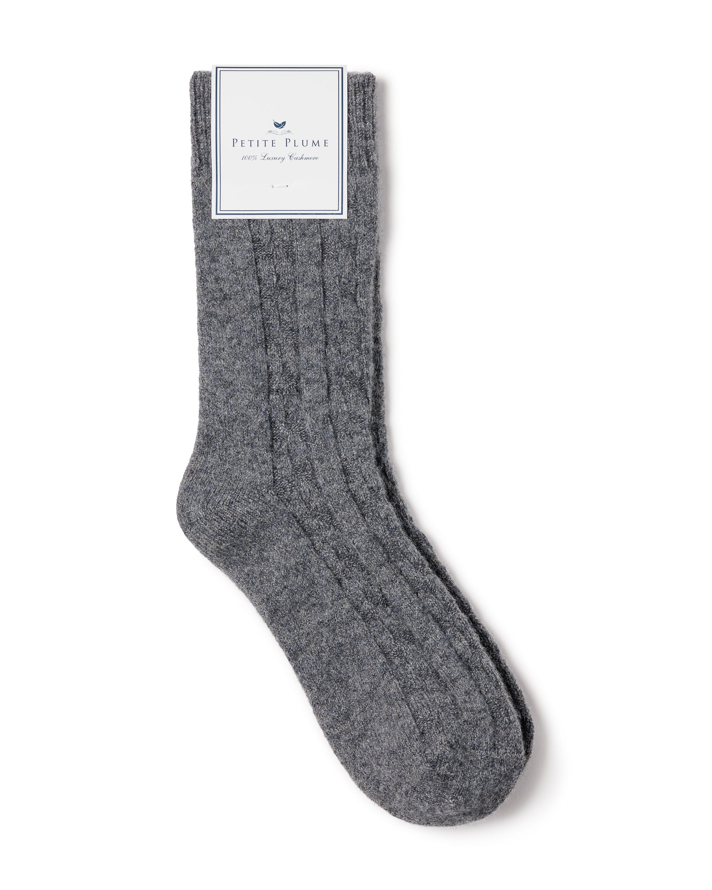 The Mens Cashmere Socks in Dark Grey by Petite Plume, with a ribbed design and elegant branding, offer luxurious comfort. Soft and cozy, they are perfect for cold weather and come in a gift box, making them an ideal present.