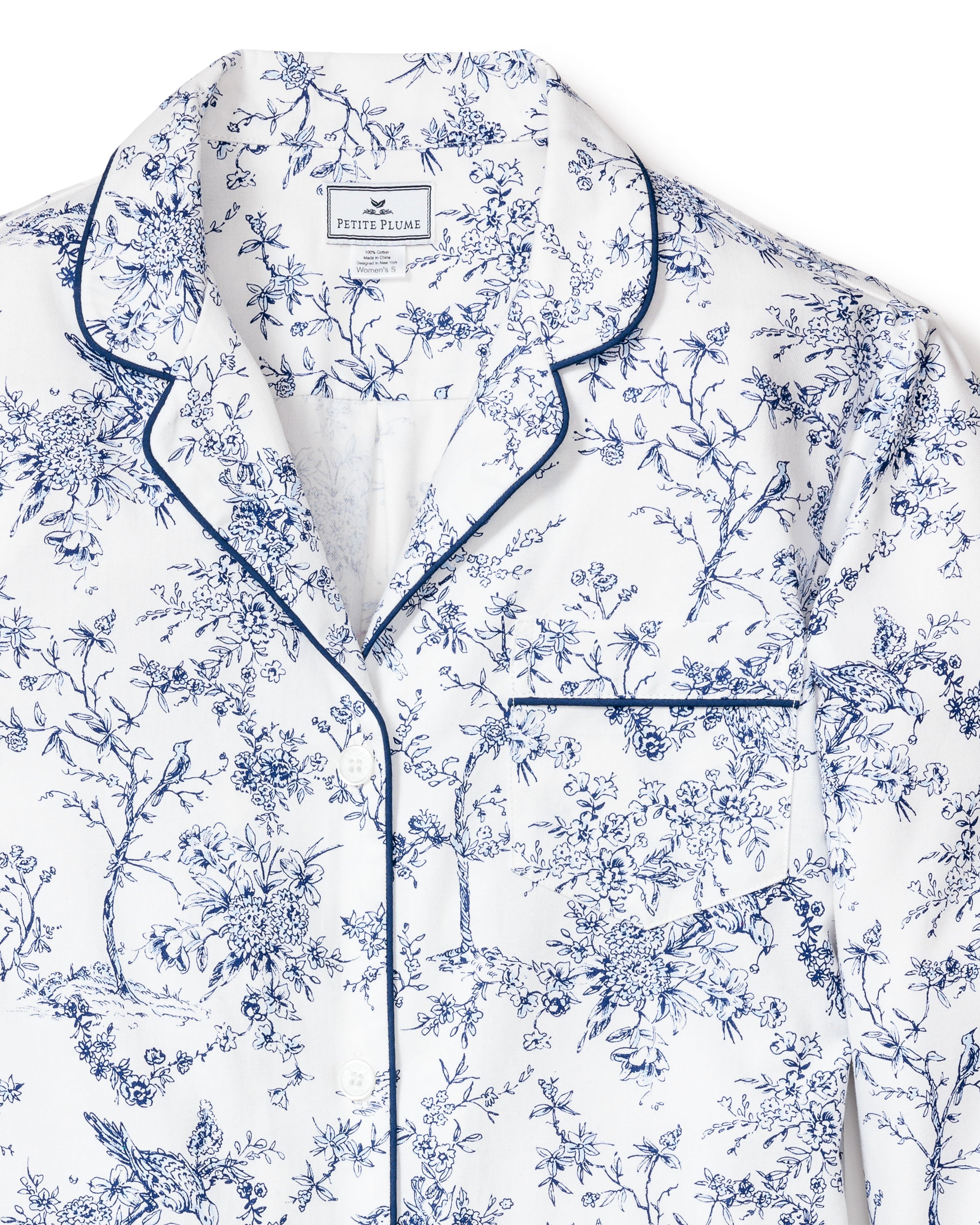 Close-up of Petite Plumes Womens Twill Long Sleeve Short Set in Timeless Toile. Featuring a blue floral pattern on fine white cotton, it includes a front pocket with navy piping on the collar, lapels, and pocket.