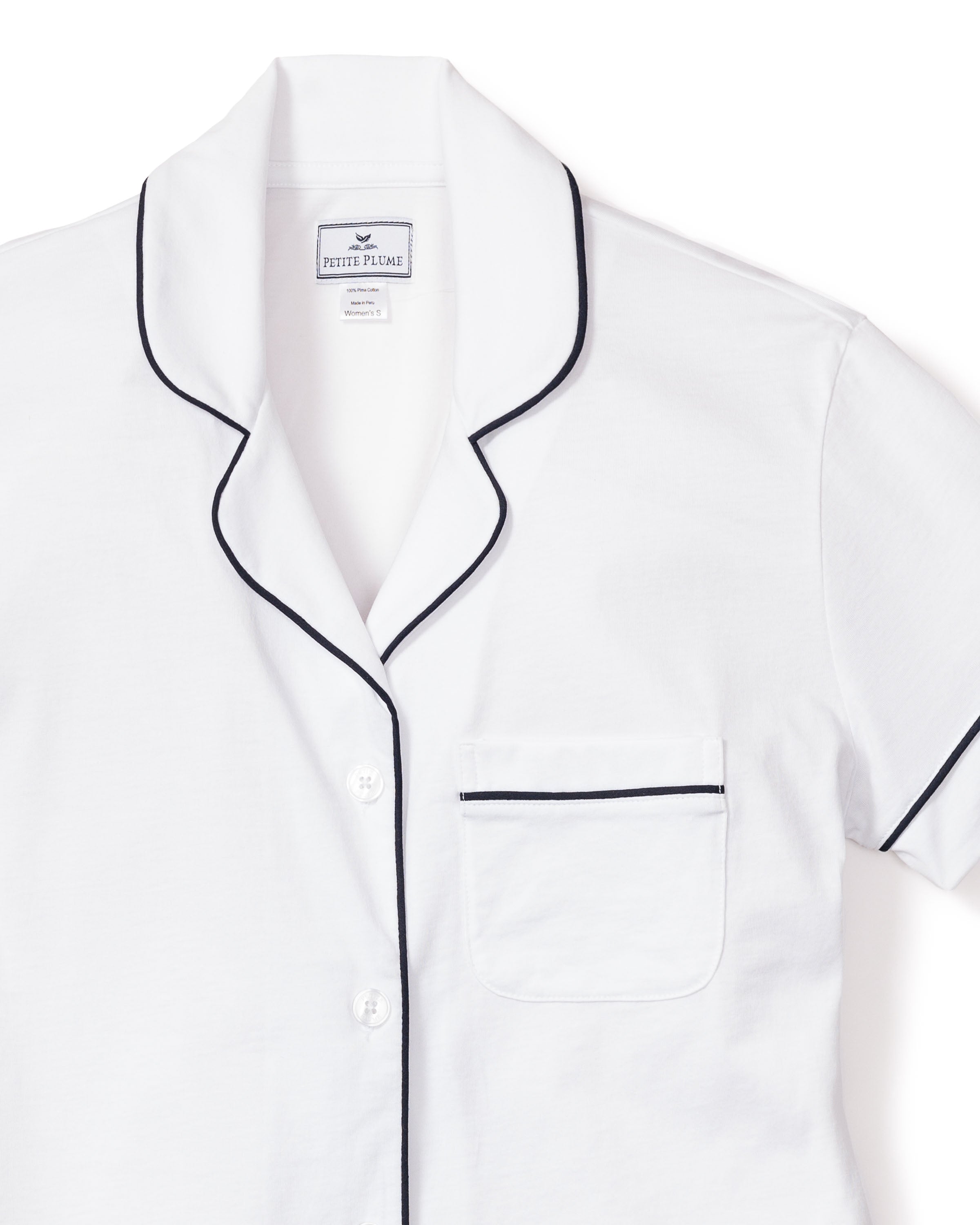 The Womens Pima Pajama Short Set by Petite Plume in white with navy piping features a cotton twill short-sleeve top, complete with black piping on the edges and collar, a left chest pocket outlined in black piping, and a button-down front for classic style—ideal for luxury bedding enthusiasts.