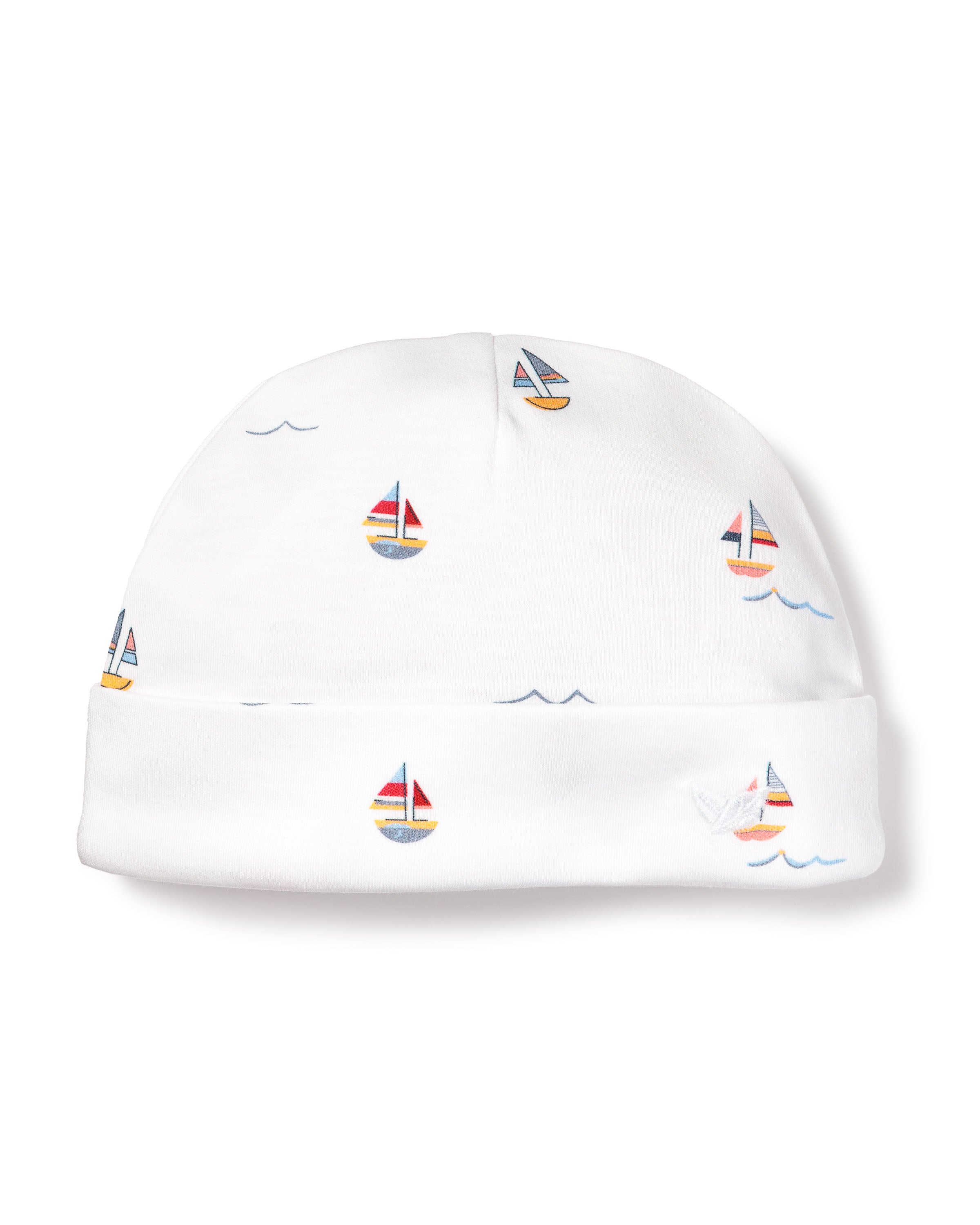 The Petite Plume Babys Pima Hat in Bateau is a whimsical white beanie made from soft Peruvian Pima Cotton, adorned with colorful sailboats featuring red, yellow, and blue sails, and tiny blue waves—an enchanting accessory for any babys outfit.