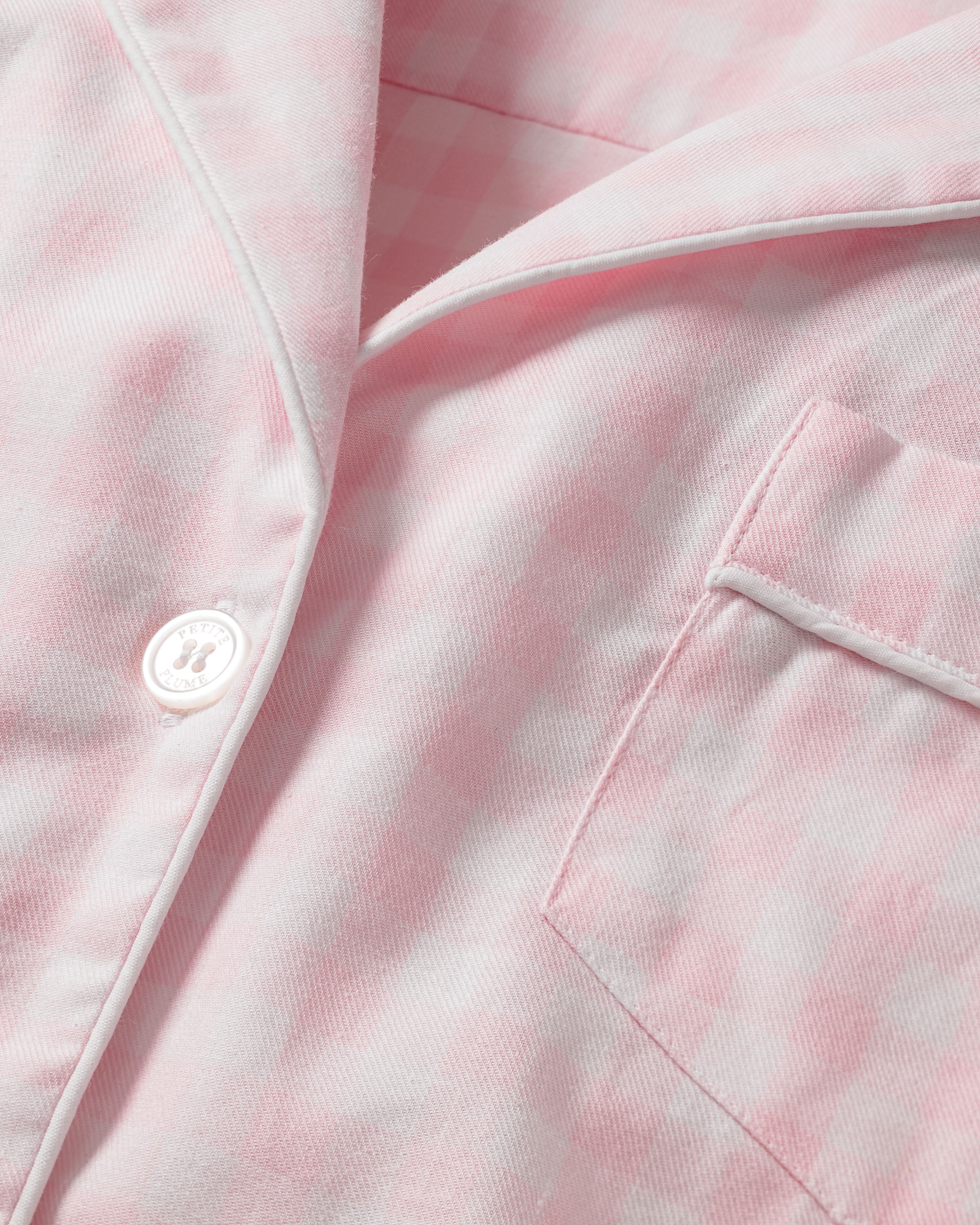 Close-up of a Womens Twill Pajama Set in Pink Gingham by Petite Plume, featuring soft pink and white gingham fabric with a button, chest pocket, collar, and white piping—ideal for cozy comfort.