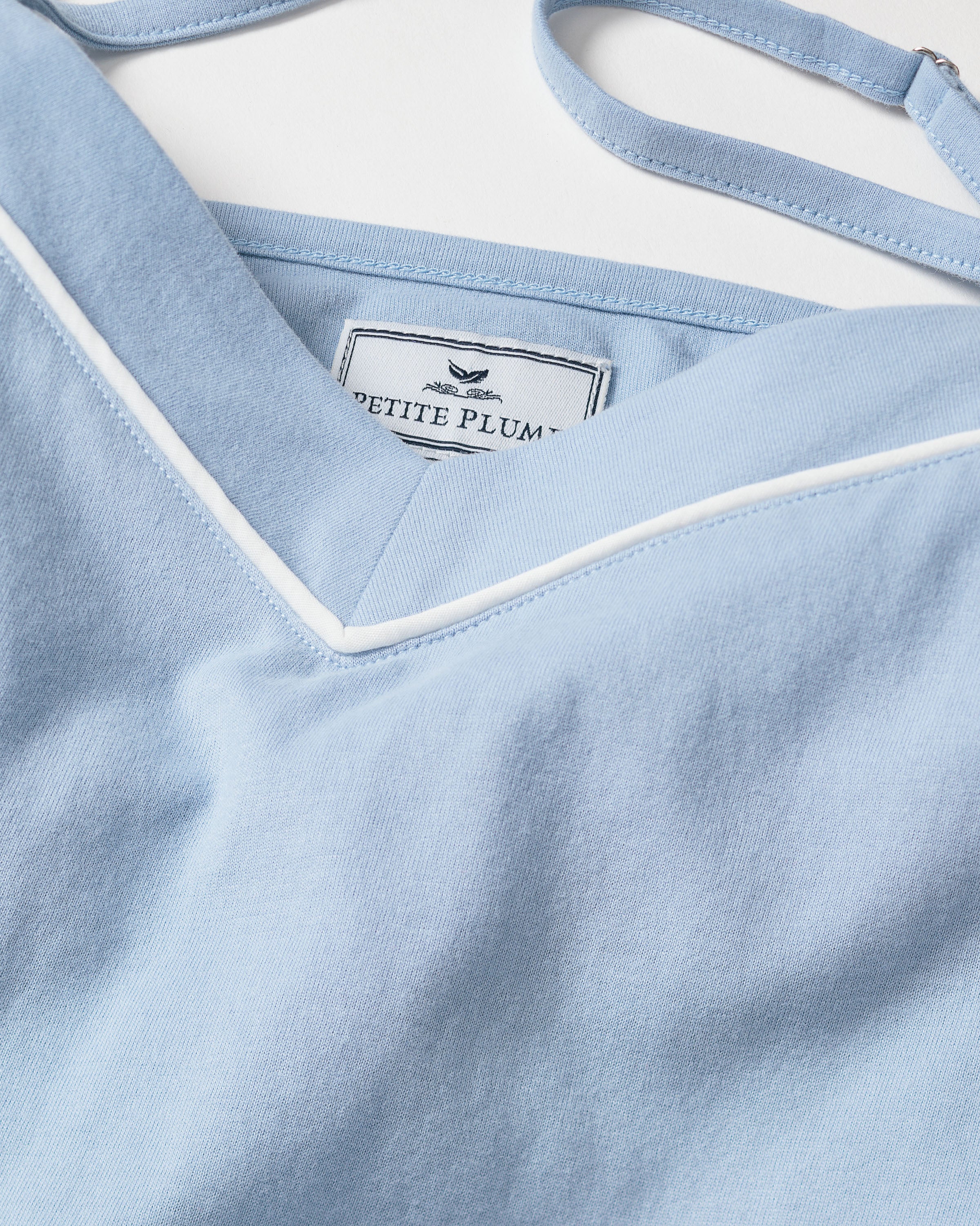 Close-up of the Periwinkle Pima Sylvie Cami Short Set by Petite Plume, showcasing the light blue with white trim. Crafted from soft Pima cotton, this nightwear might include a comfortable shelf bra for added support.