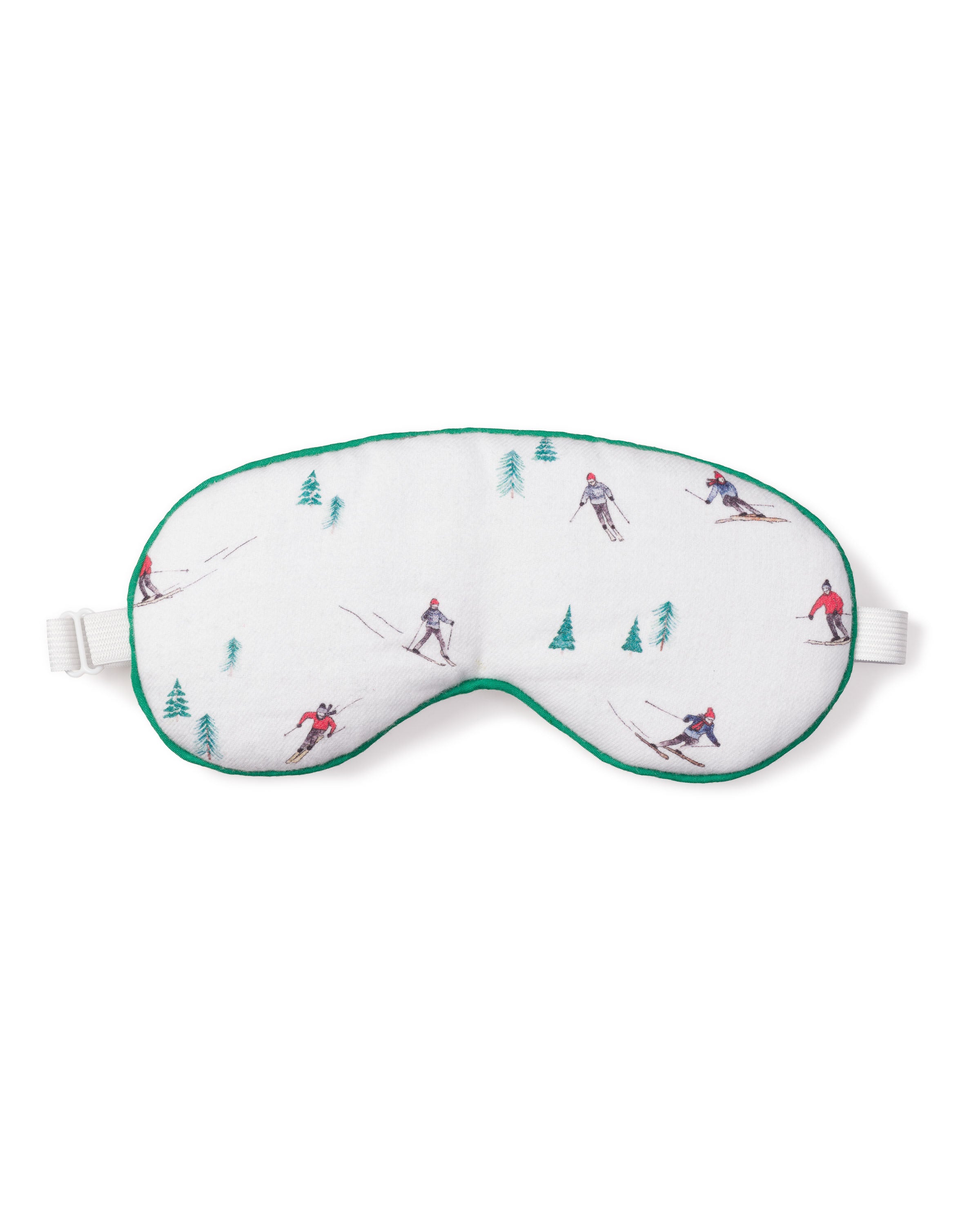 The Adults Flannel Sleep Mask in Après Ski by Petite Plume features a luxurious white design with skiing illustrations and green trees, a delicate green edge, and an adjustable strap for comfort. Ideal for those looking for matching or monogrammed eye masks.