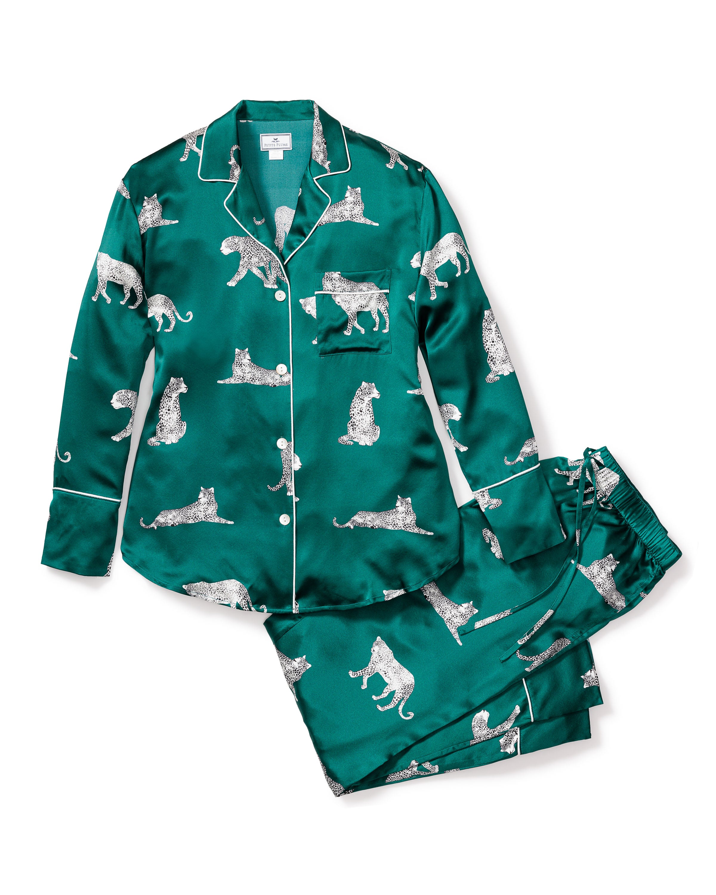 Discover elegance with the Womens Silk Pajama Set in Panthère de Luxe by Petite Plume, featuring a green long-sleeved button-up shirt and pants adorned with white panther illustrations for exquisite relaxation.