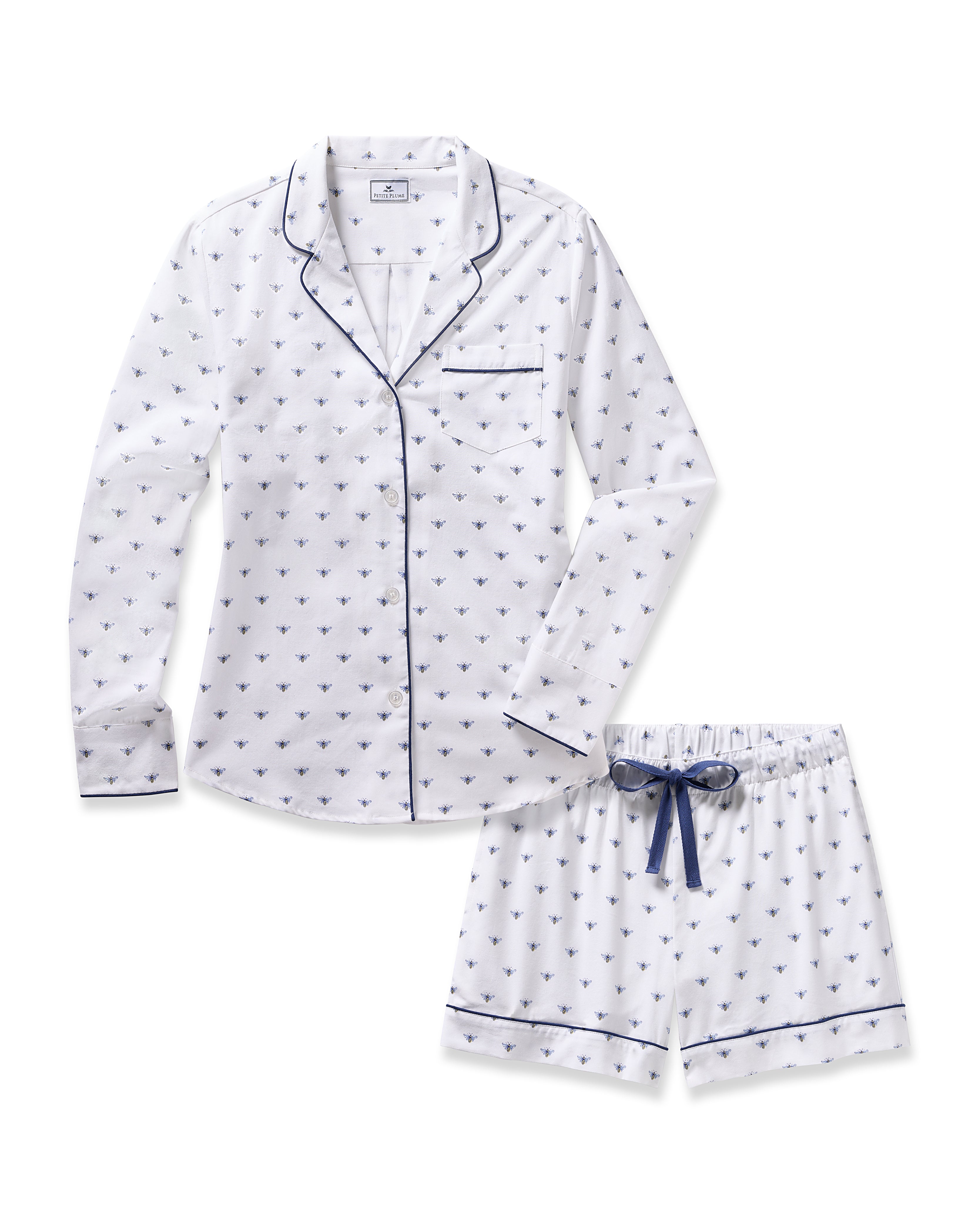 The Womens Twill Long Sleeve Short Set in Buzzing Bees by Petite Plume is a luxurious sleepwear set crafted from high-quality cotton. It features a charming bee pattern, long-sleeve shirt with dark blue piping and chest pocket, and shorts with a dark blue drawstring for comfort.