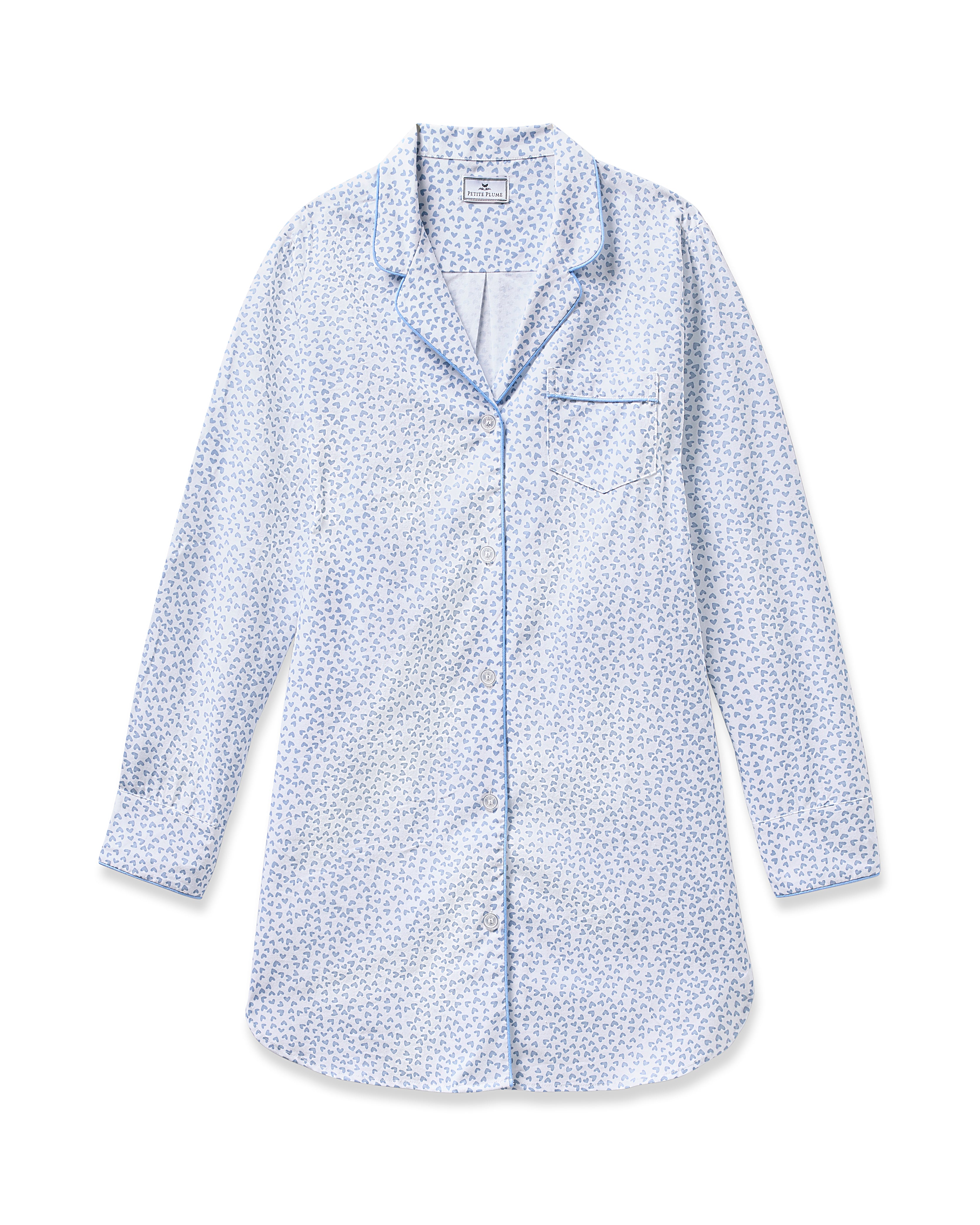 The Womens Twill Nightshirt in Bluehearts by Petite Plume is a light blue pajama top made from soft cotton twill. It features a small floral pattern, blue piping accents, a notched collar, button-down front, and a chest pocket for added simplicity.