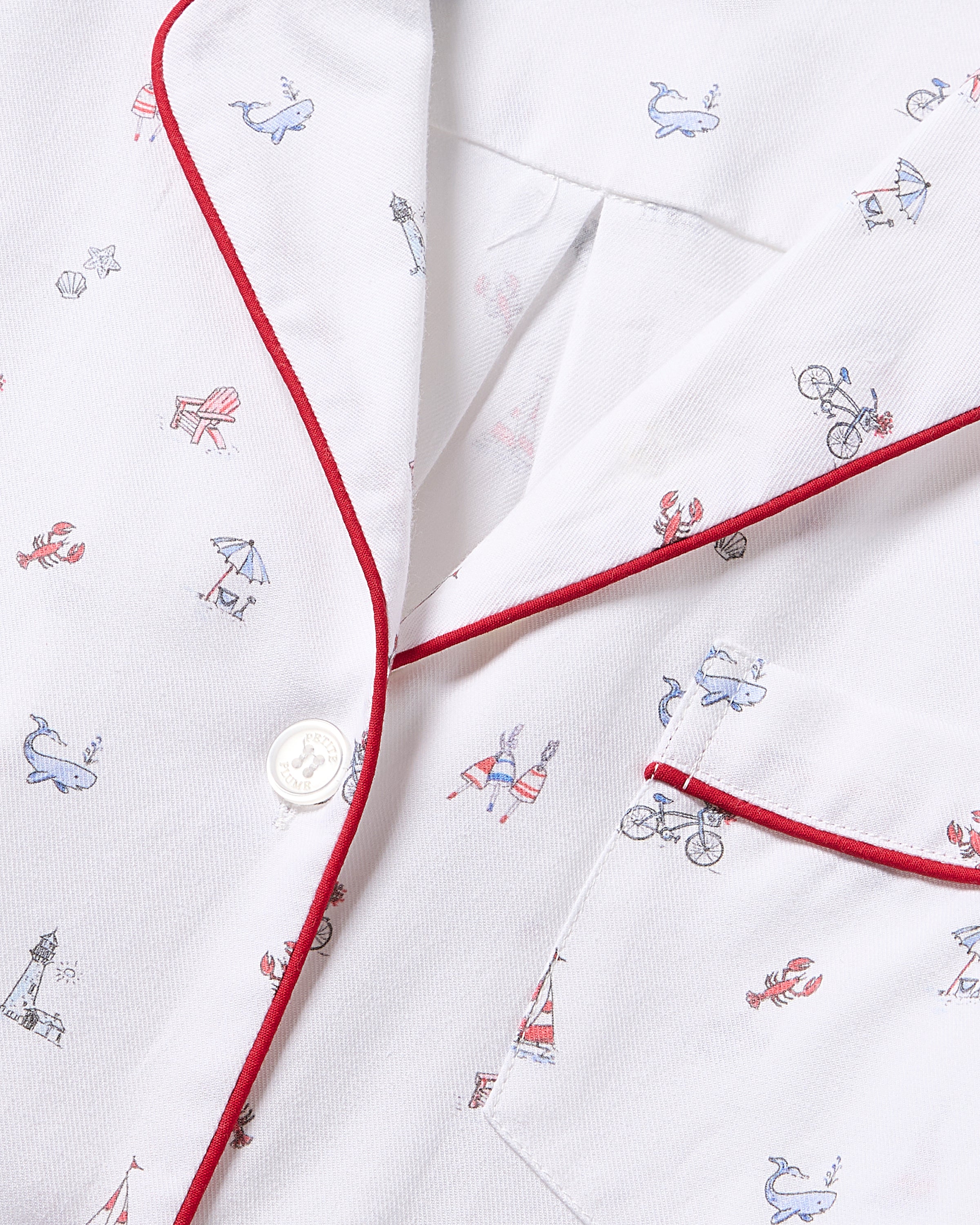 Close-up of Petite Plumes Womens Twill Nightshirt in white cotton adorned with whimsical Coastal Charms like whales, lobsters, and sailboats. Red piping and buttons add flair to this delightful coastal design.