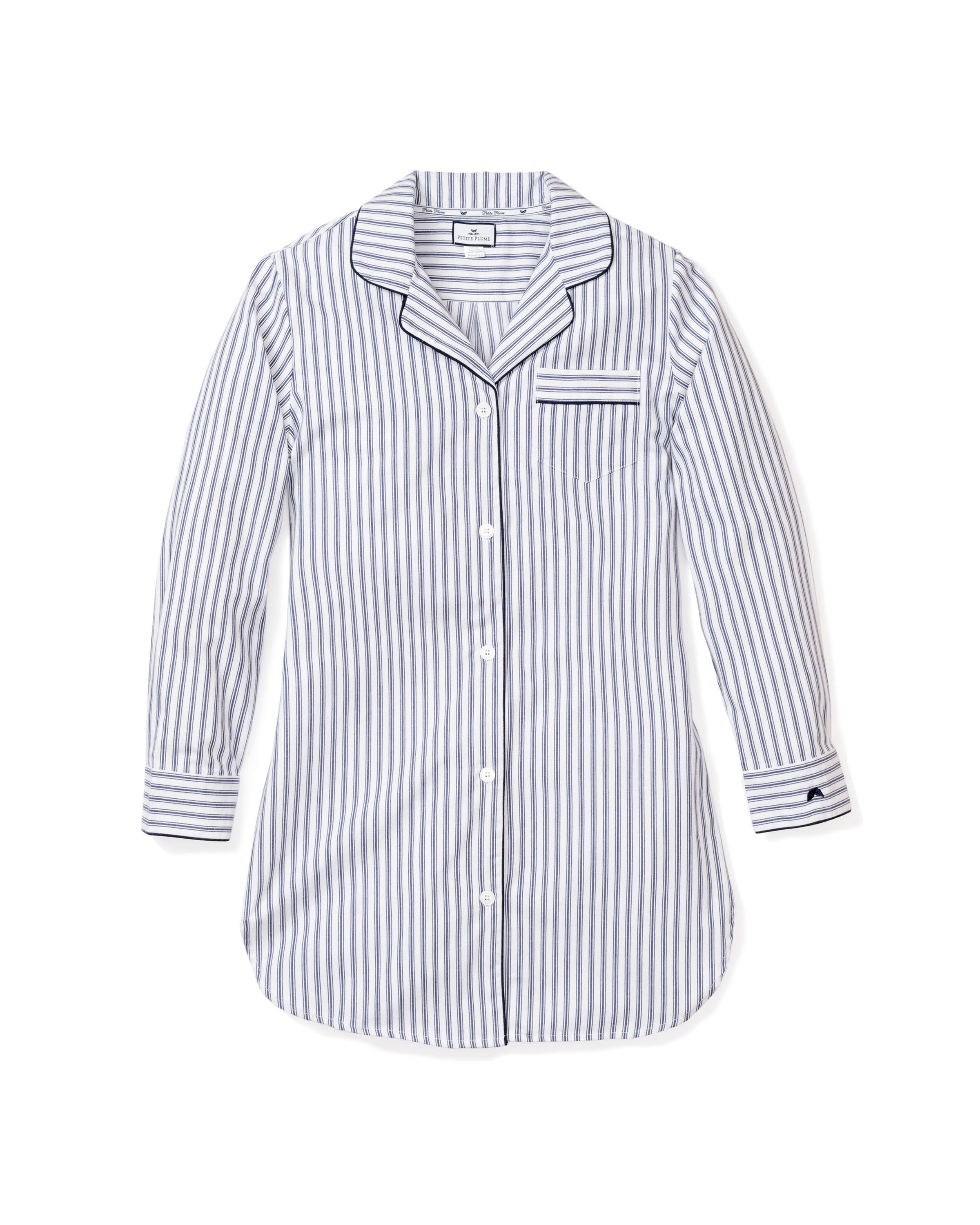 The Womens Twill Nightshirt in Navy French Ticking by Petite Plume is a long-sleeved, button-up nightshirt with a classic pajama design featuring blue and white vertical stripes, soft cotton twill, a chest pocket, and black piped trim on the collar, front, and cuffs.