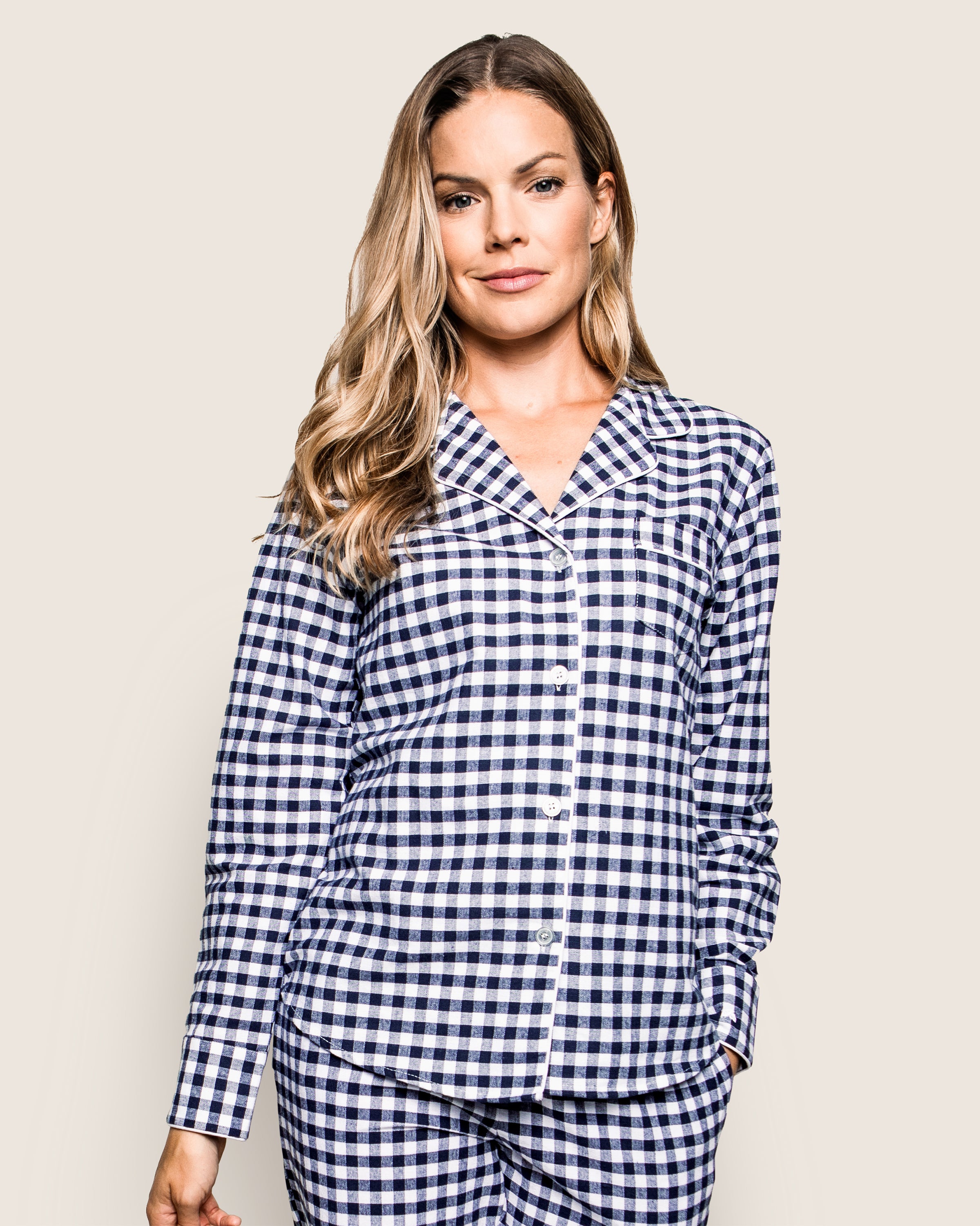 A person in a Petite Plume Womens Twill Pajama Set in Navy Gingham poses against a plain background. The comfy cotton twill set includes a button-up top with long sleeves and a collar, while the persons hair is long and wavy.