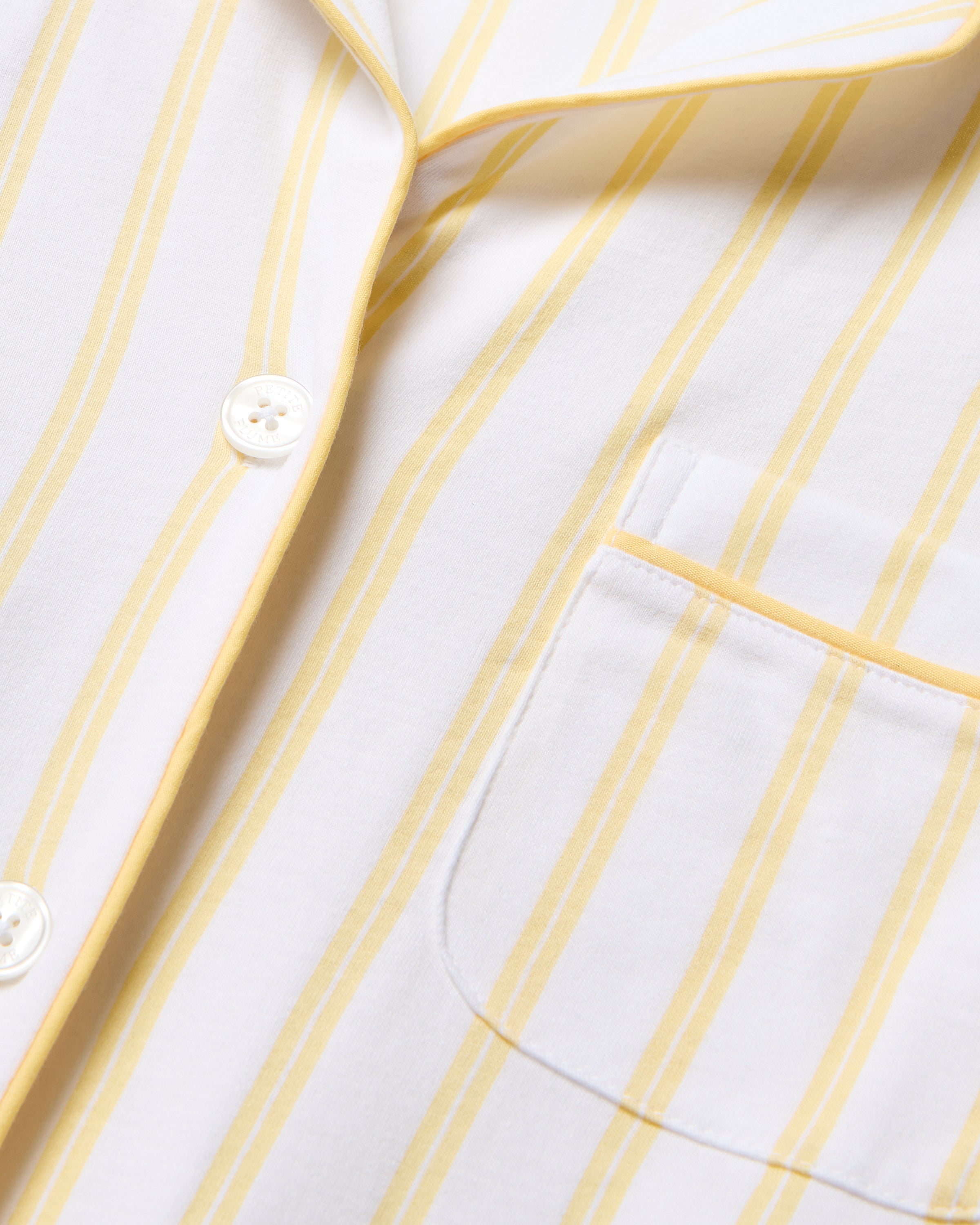 Close-up of Petite Plumes Womens Pima Pajama in Sunny Stripe, crafted from buttery soft fabric with white and yellow vertical stripes. The image highlights the collar, a pocket, and three white buttons on one side—luxury sleepwear elegance in every stitch.