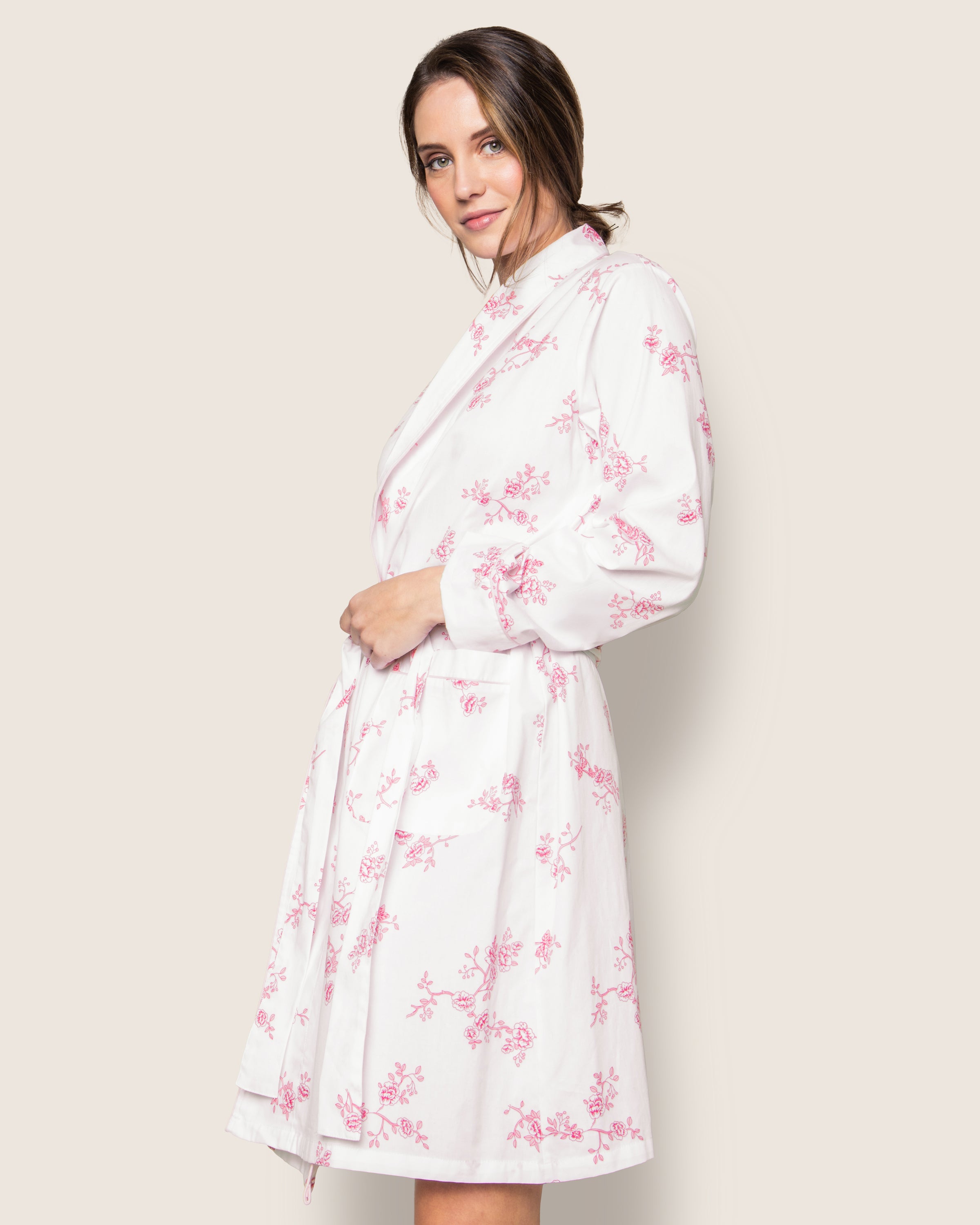 A woman in a Womens Twill Robe in English Rose Floral by Petite Plume poses against a light background. Made from premium cotton sleepwear, the robe features long sleeves and a tied waist for an elegant, comfortable fit.