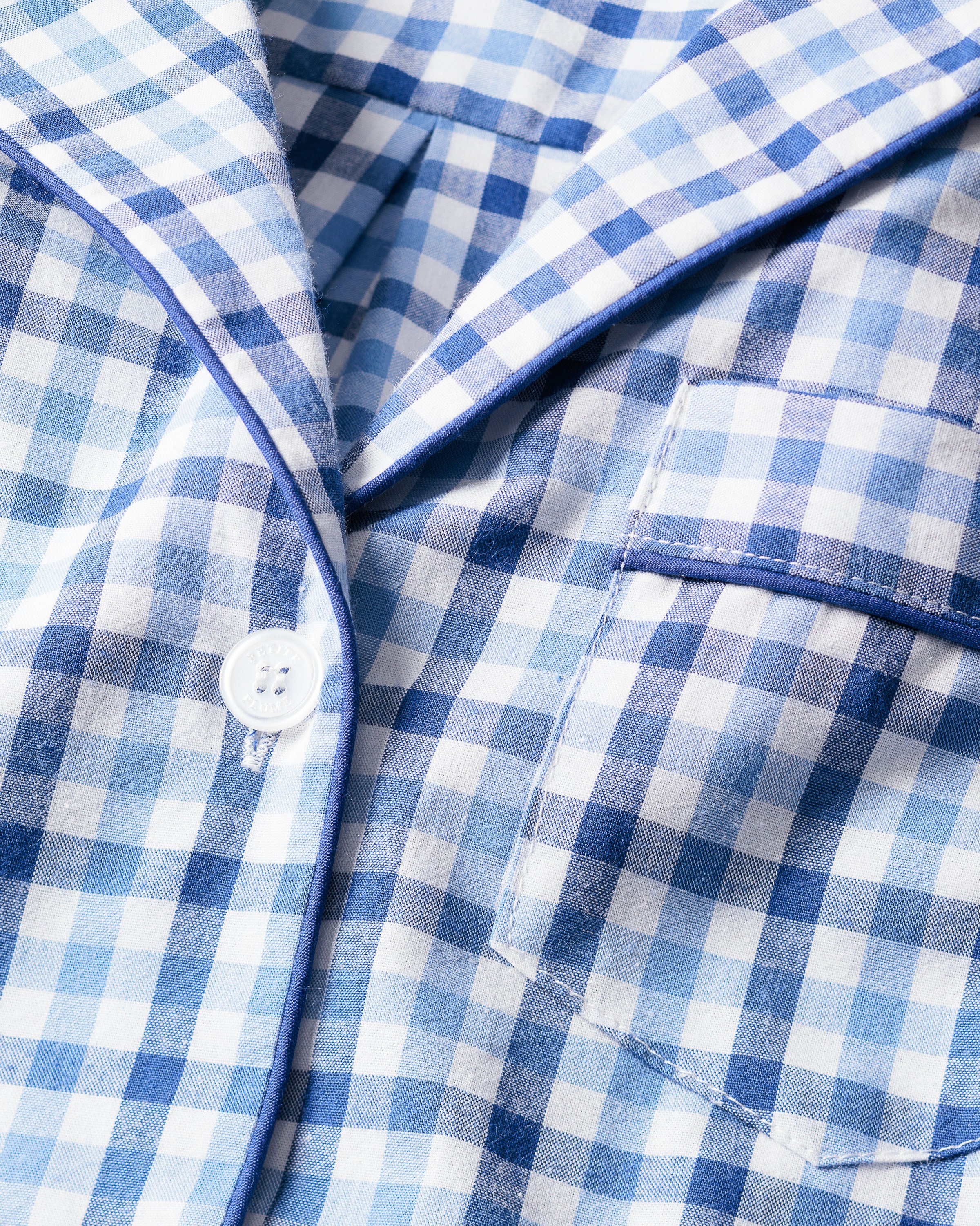 Close-up of Petite Plumes Womens Twill Pajama Short Sleeve Short Set in Royal Blue Gingham: a soft, luxury sleepwear with button-up design, classic check pattern, a pocket, and thin blue piping on the edges.