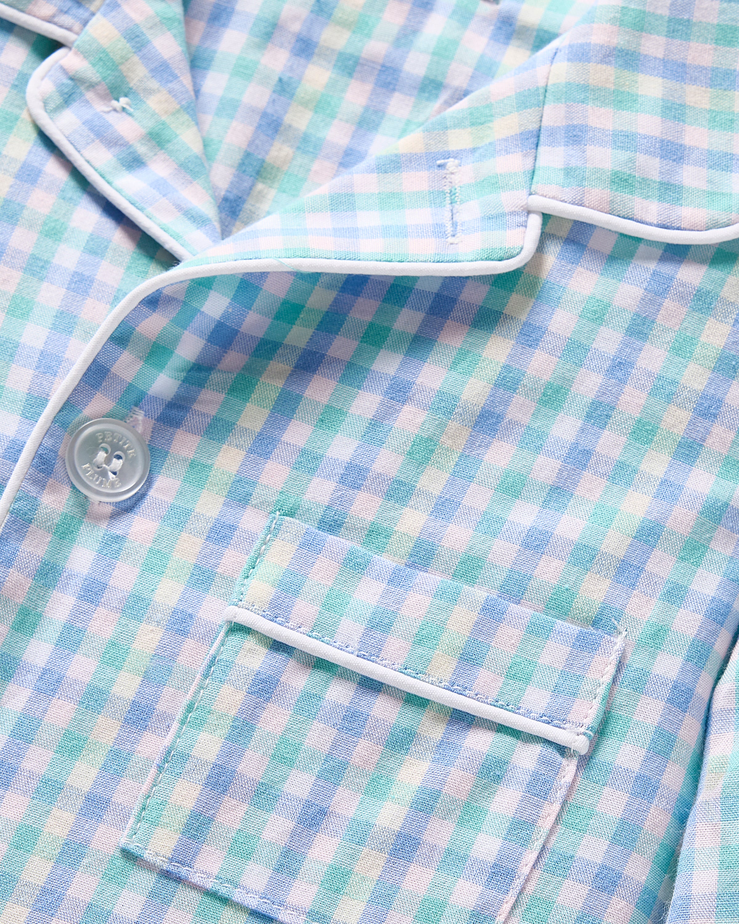 Close-up of Kids Twill Pajama Shirt by Petite Plume in Spring Gingham. Made from soft yarn-dyed cotton with light blue and green plaid, white buttons, piping, and a pattern-matching pocket, its a cozy choice for any pajama set.