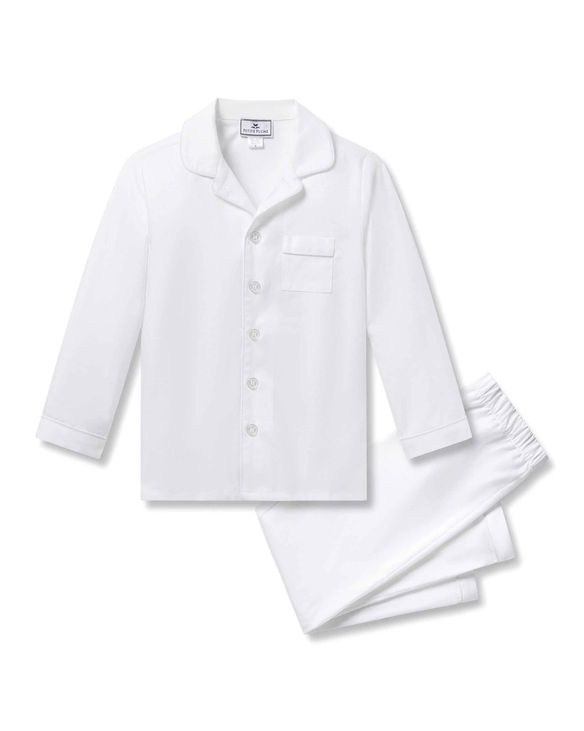 The Kids Twill Pajama Set from Petite Plume, in white with white piping, features a luxurious cotton long-sleeve button-up top with a chest pocket and matching pants. Its simple, classic design ensures ultimate comfort and restful sleep.