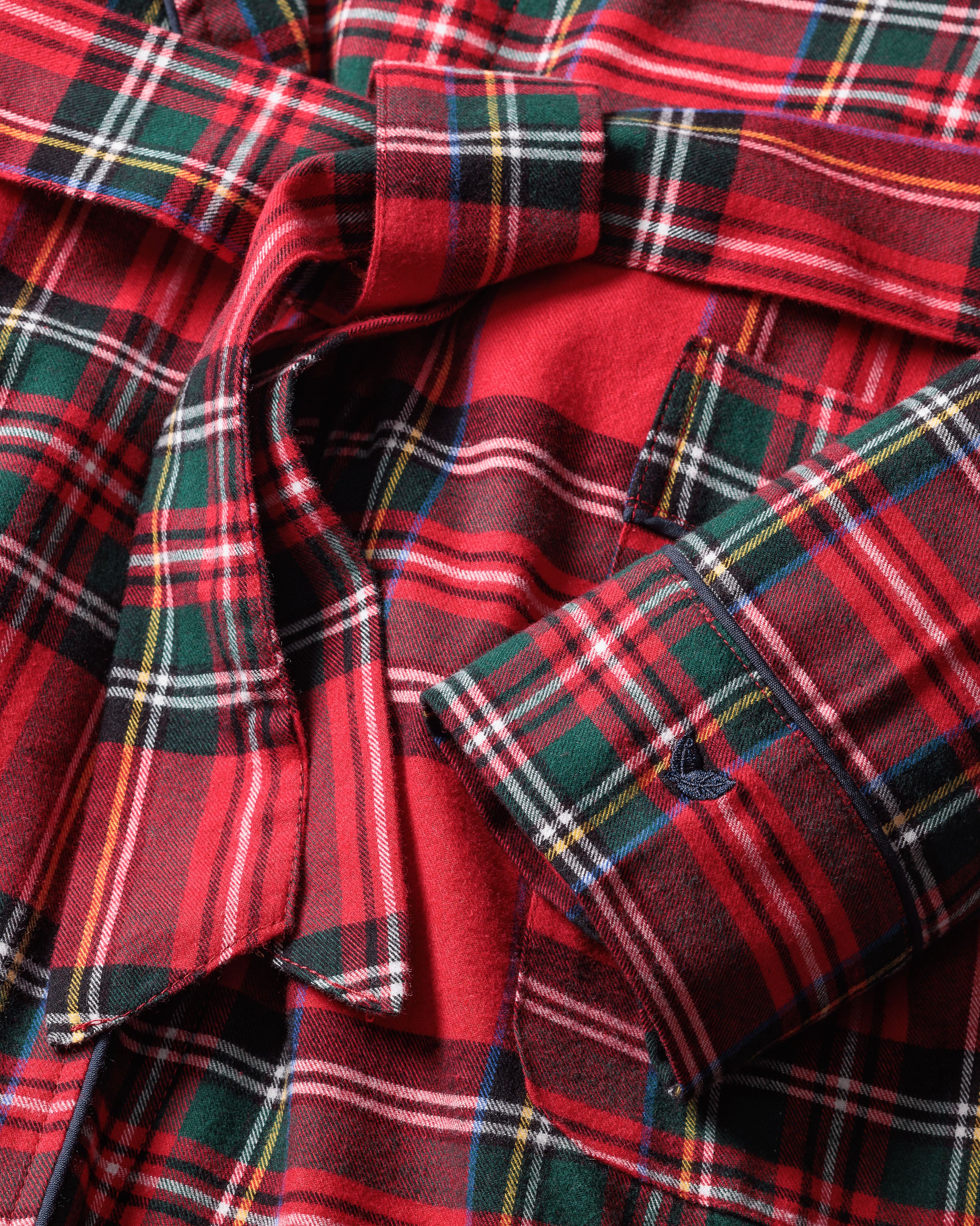 Close-up of Petite Plumes Kids Brushed Cotton Robe in Imperial Tartan, made from lightweight soft cotton with red plaid featuring green, white, and yellow stripes. The yarn-dyed design highlights folded sleeves and button details.