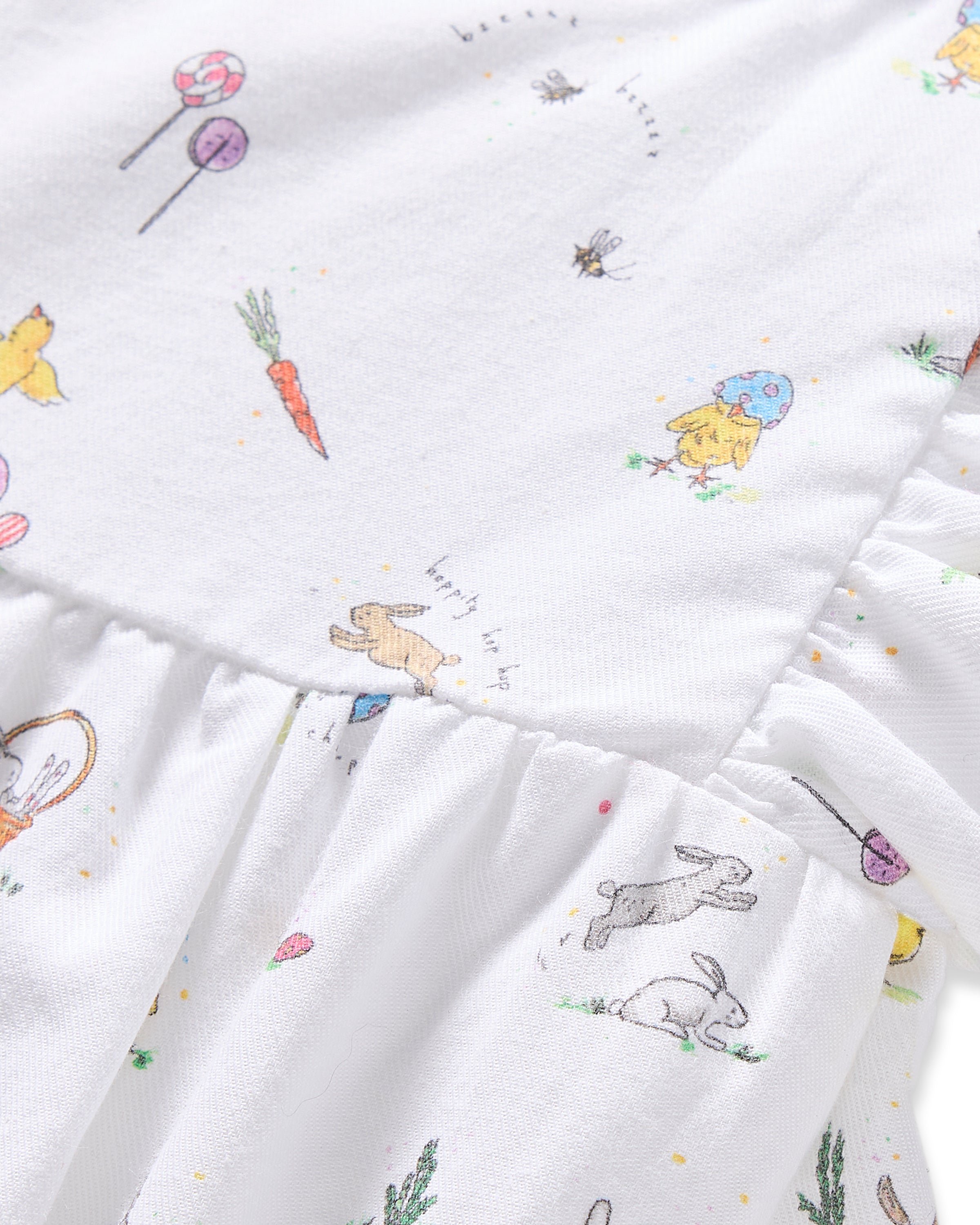 Close-up of Petite Plumes Babys Twill Ruffled Romper in Easter Frolic, a luxurious cotton fabric with rabbits, chicks, carrots, flowers, and balloons. The sleepwear features charming ruffled detailing.