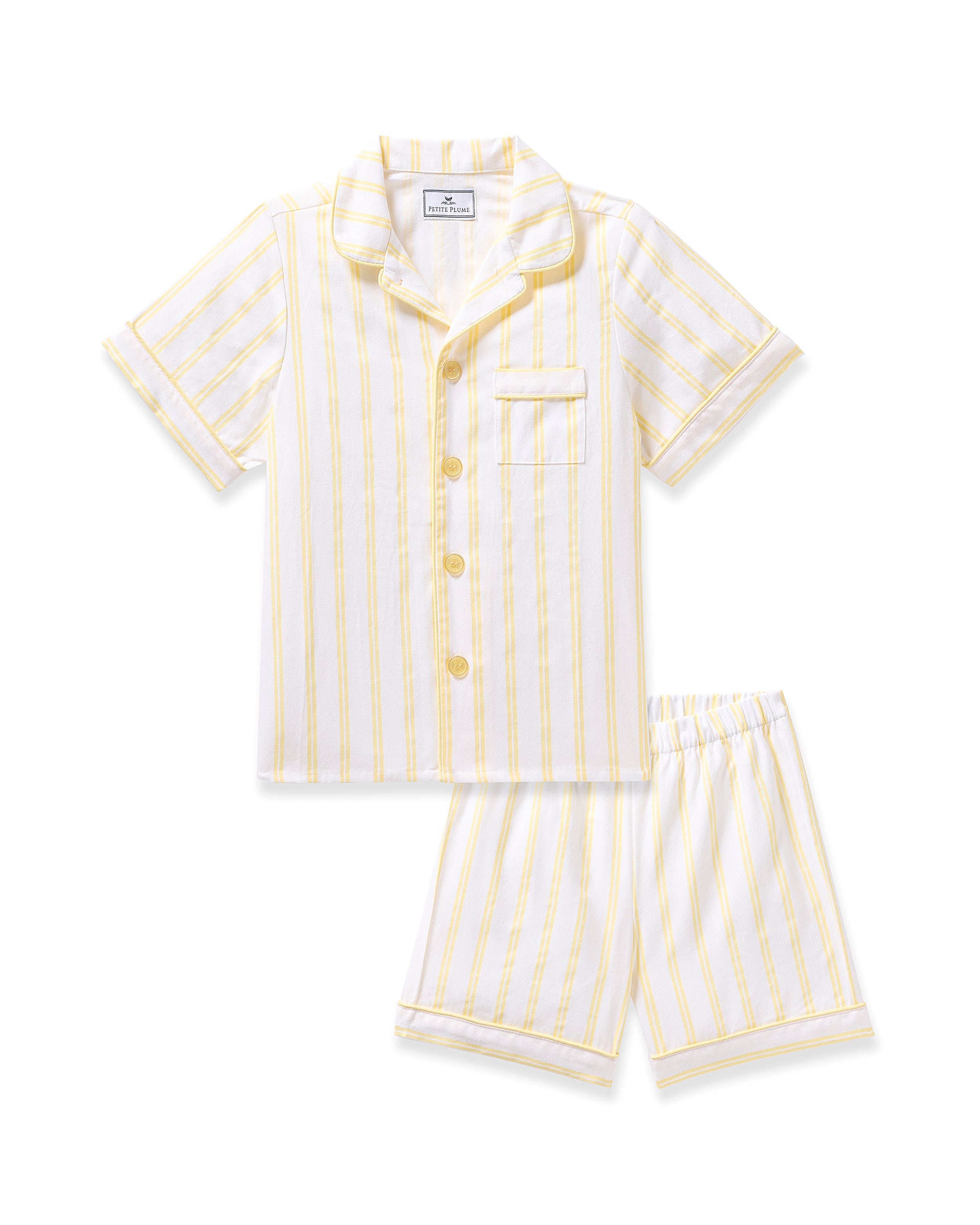 The Kids Twill Short Sleeve Short Set in Sunny Stripe by Petite Plume is soft cotton sleepwear featuring a white and yellow striped pattern. It includes a short-sleeved button-up top with a chest pocket and matching shorts.