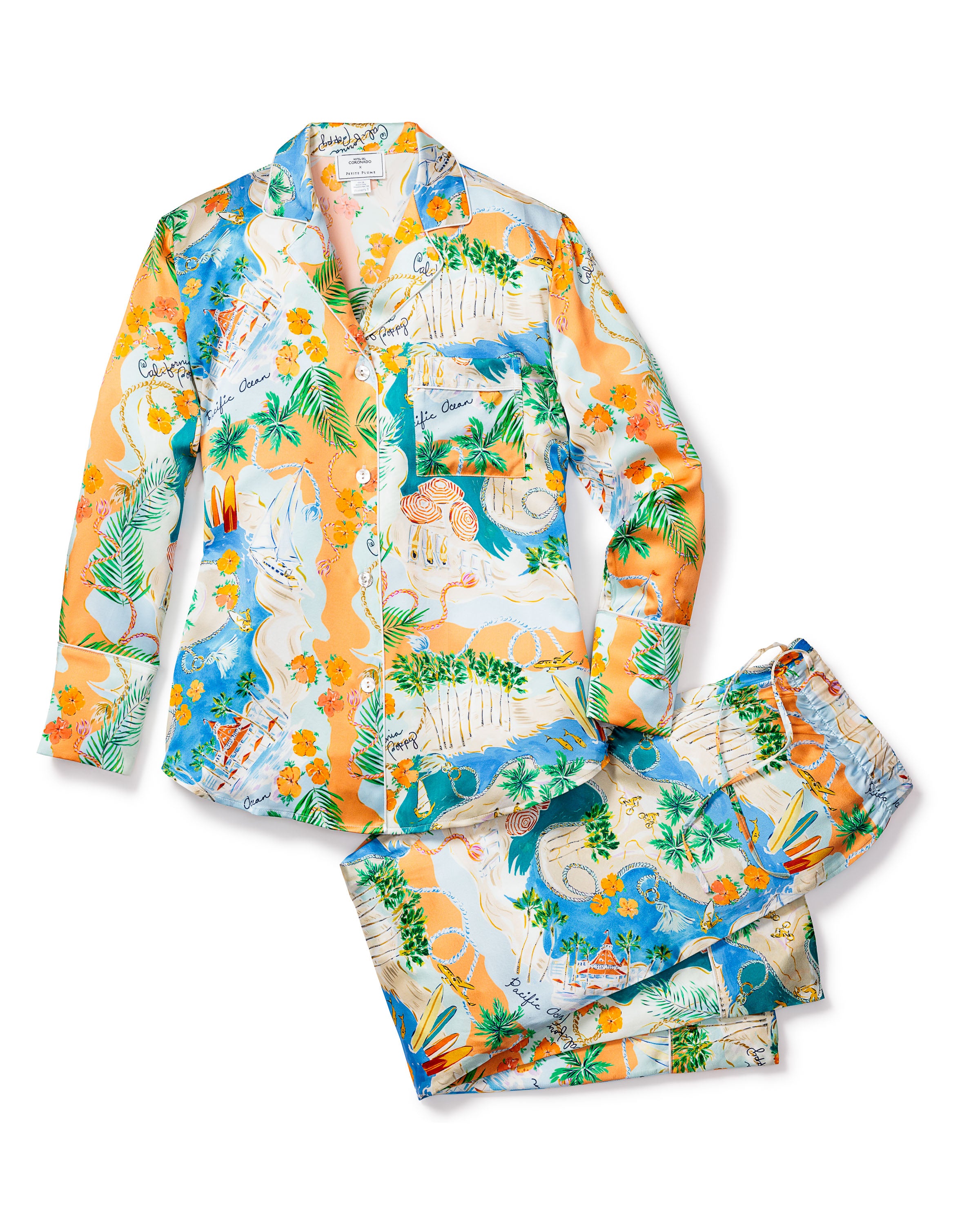 Indulge in luxury with the Womens Silk Print Pajama Set by Petite Plume, inspired by Hotel del Coronado. This set features a vibrant tropical theme in orange and blue, with patterns of palm leaves, pineapples, and white tigers on a pure silk long-sleeve button-up shirt and pants.