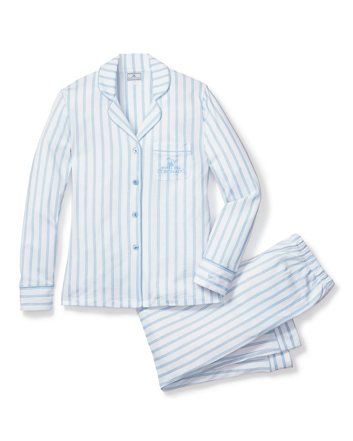 The Womens Pima Pajama Set by Petite Plume, a collaboration with Hotel del Coronado, features luxuriously soft yarn-dyed Peruvian Pima cotton in a light blue and white stripe. The long-sleeve shirt includes a collar, button-up front, and embroidered chest pocket logo, paired with pants featuring an elastic waistband.