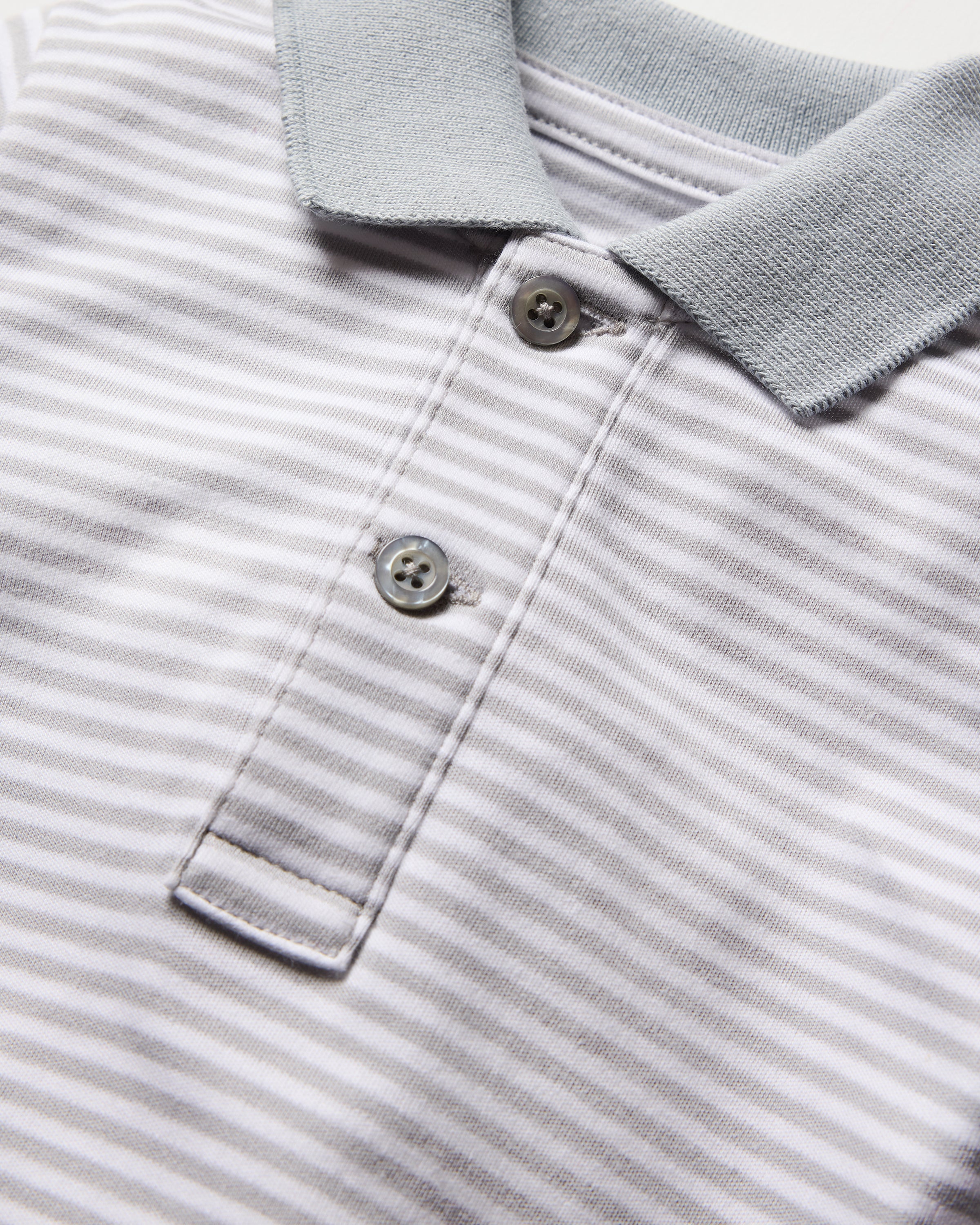 Close-up of Petite Plumes Babys Pima Louis Play Romper in Grey Stripe, featuring soft Pima cotton with grey collar, two front buttons, and neatly folded edges.