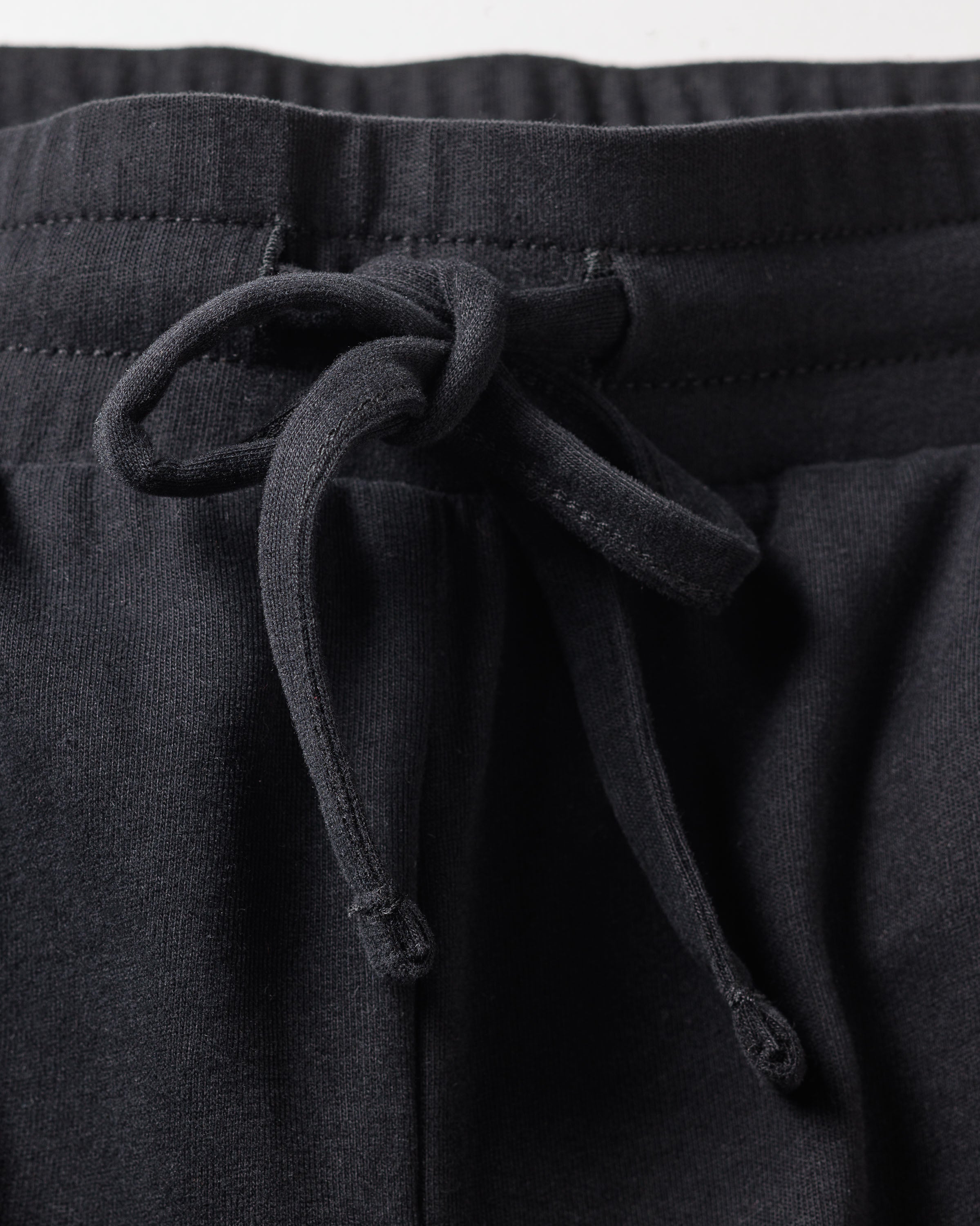 Zoom in on the Womens Pima Lounge Pants by Petite Plume, showcasing their elastic waistband and drawstring. Crafted from luxurious Peruvian Pima cotton, these black pants offer soft comfort for lounging or working out.