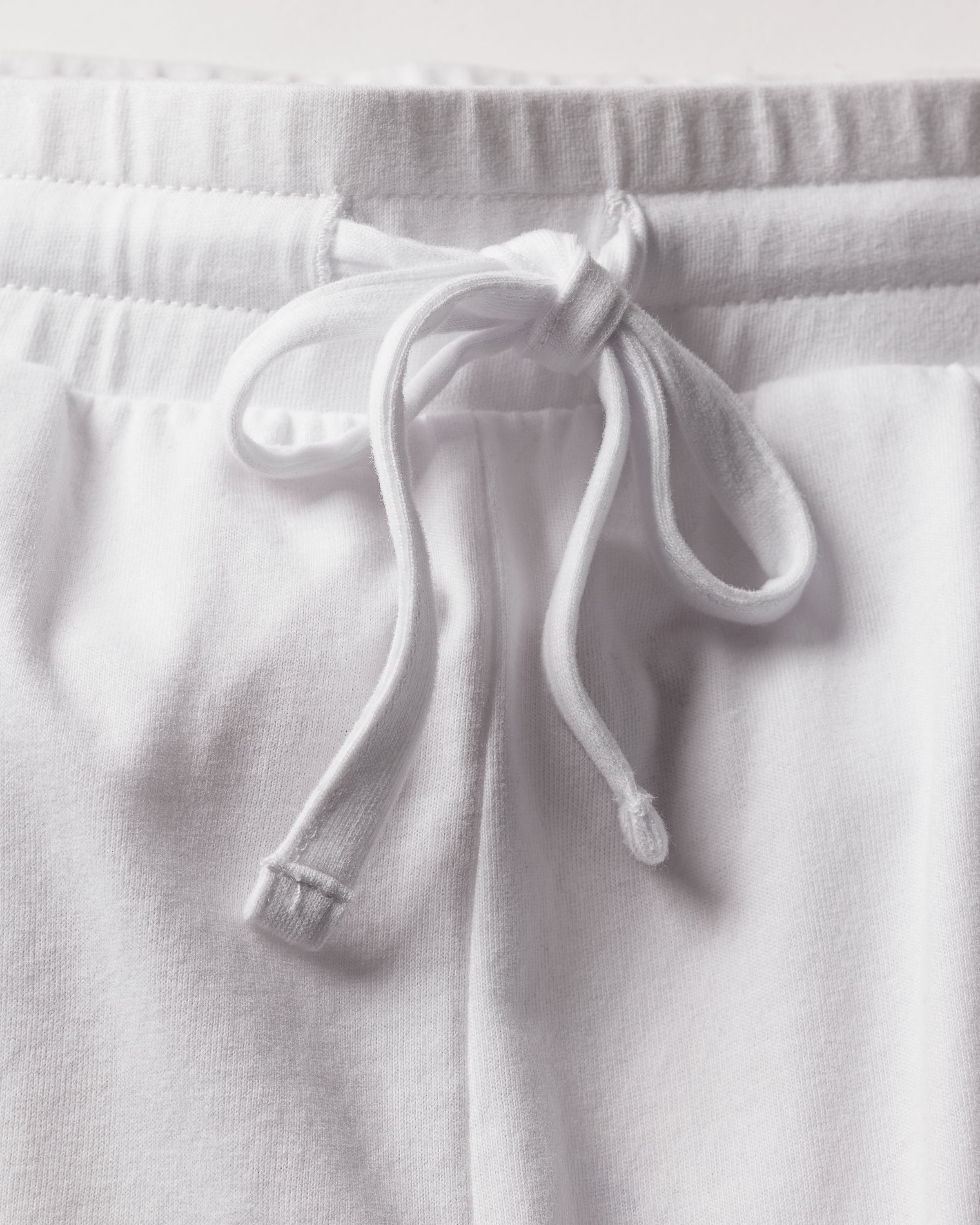 Close-up of Womens Pima Lounge Pants in White by Petite Plume, crafted from Peruvian Pima cotton with an elastic waistband and tied drawstring. The soft, textured fabric is perfect for enhancing your bedtime ritual.