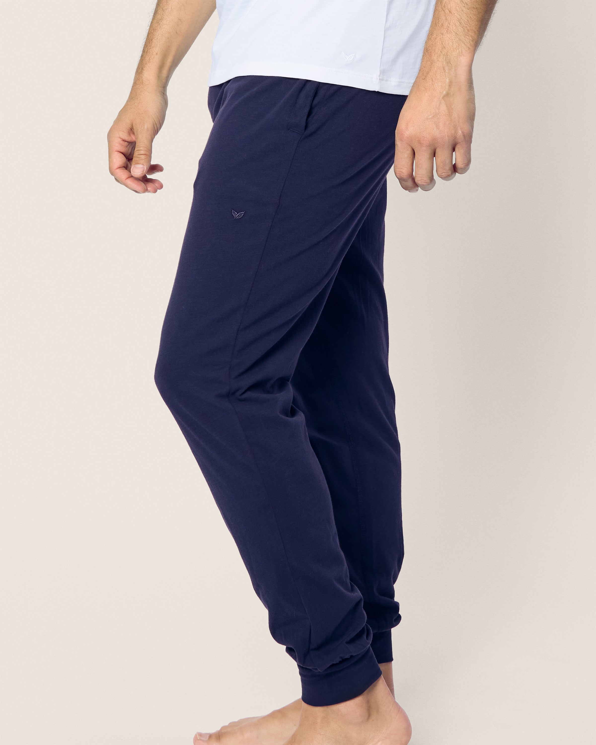 A person stands barefoot in a light-colored shirt and Petite Plumes Mens Pima Pants in Navy, made of luxurious Peruvian Pima cotton. Viewed from the side against a plain background, they exude comfort and effortless style with the jersey knit fabric.