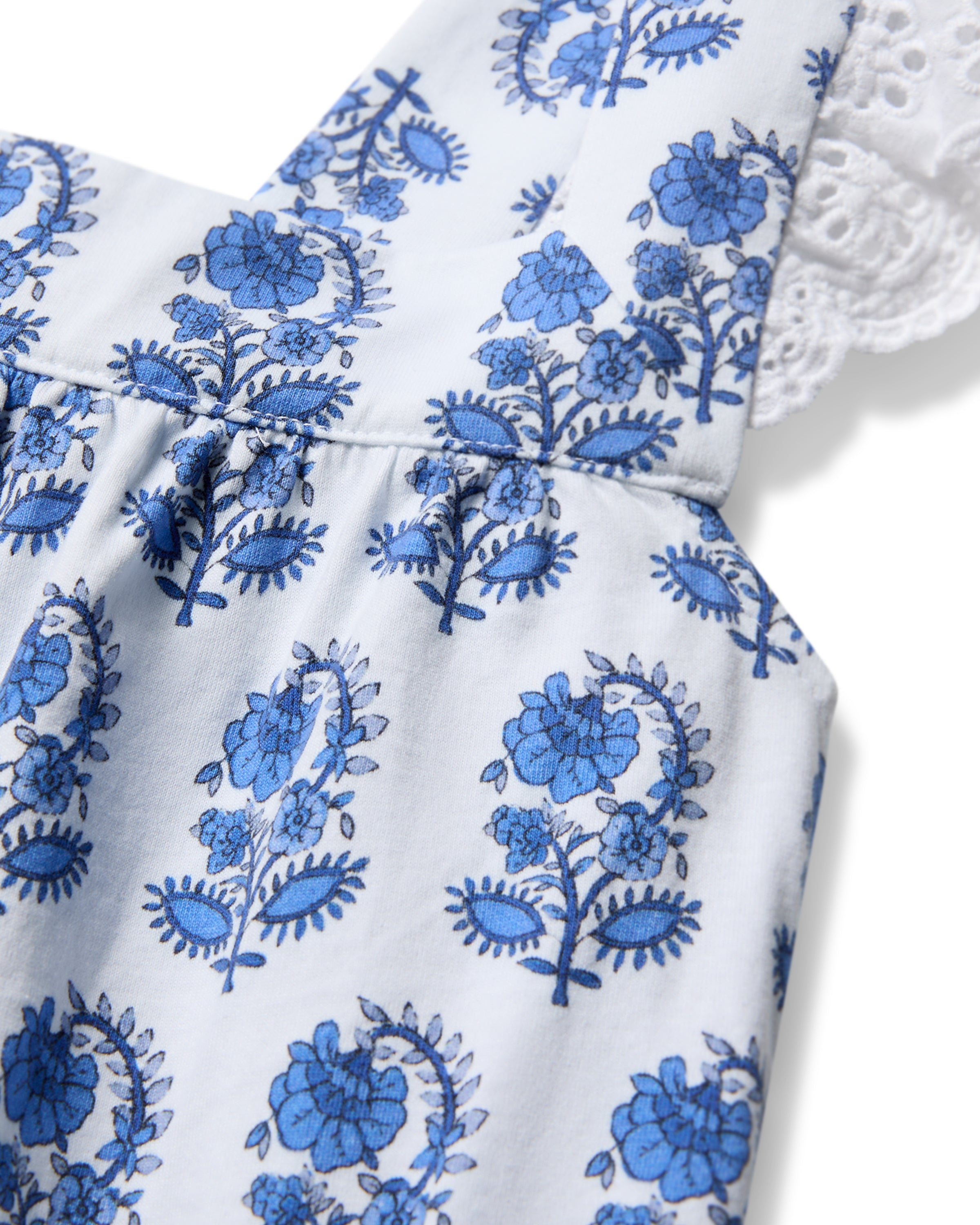 Close-up of a light blue dress with blue floral patterns and intricate detailing, crafted from Peruvian Pima cotton. This dress resembles Petite Plumes Womens Pima Clara Short Set in Bristol Bay, featuring lace-trimmed shoulder straps.