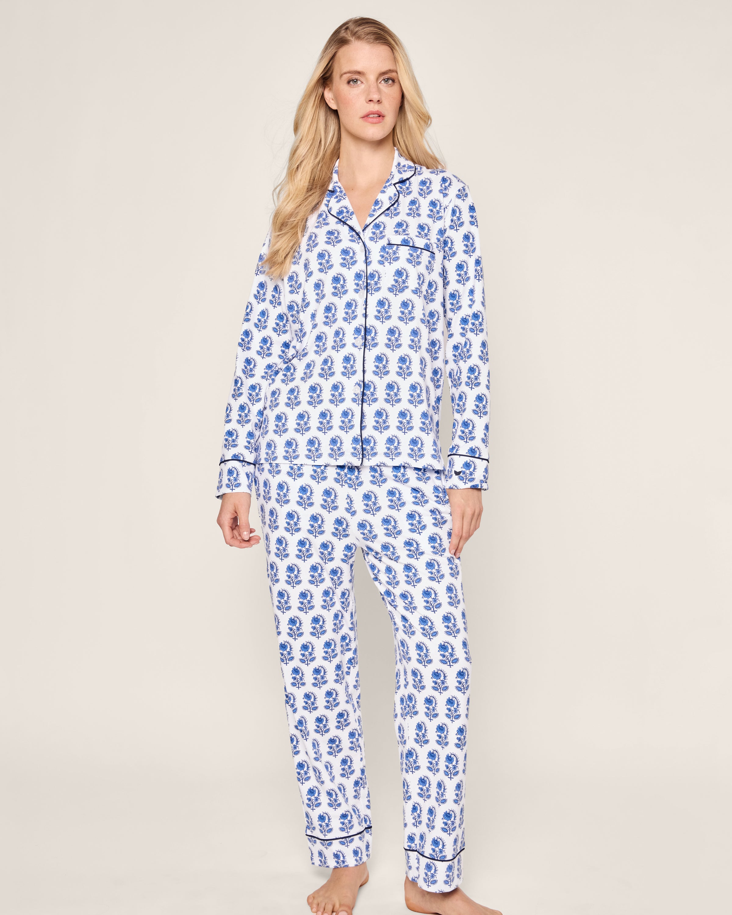 Against a plain background, someone wears the Womens Pima Pajama Set in Bristol Bay by Petite Plume. The luxurious white pajamas feature graphic florals and are crafted from the finest Peruvian Pima cotton for unmatched comfort and style in luxury sleepwear.