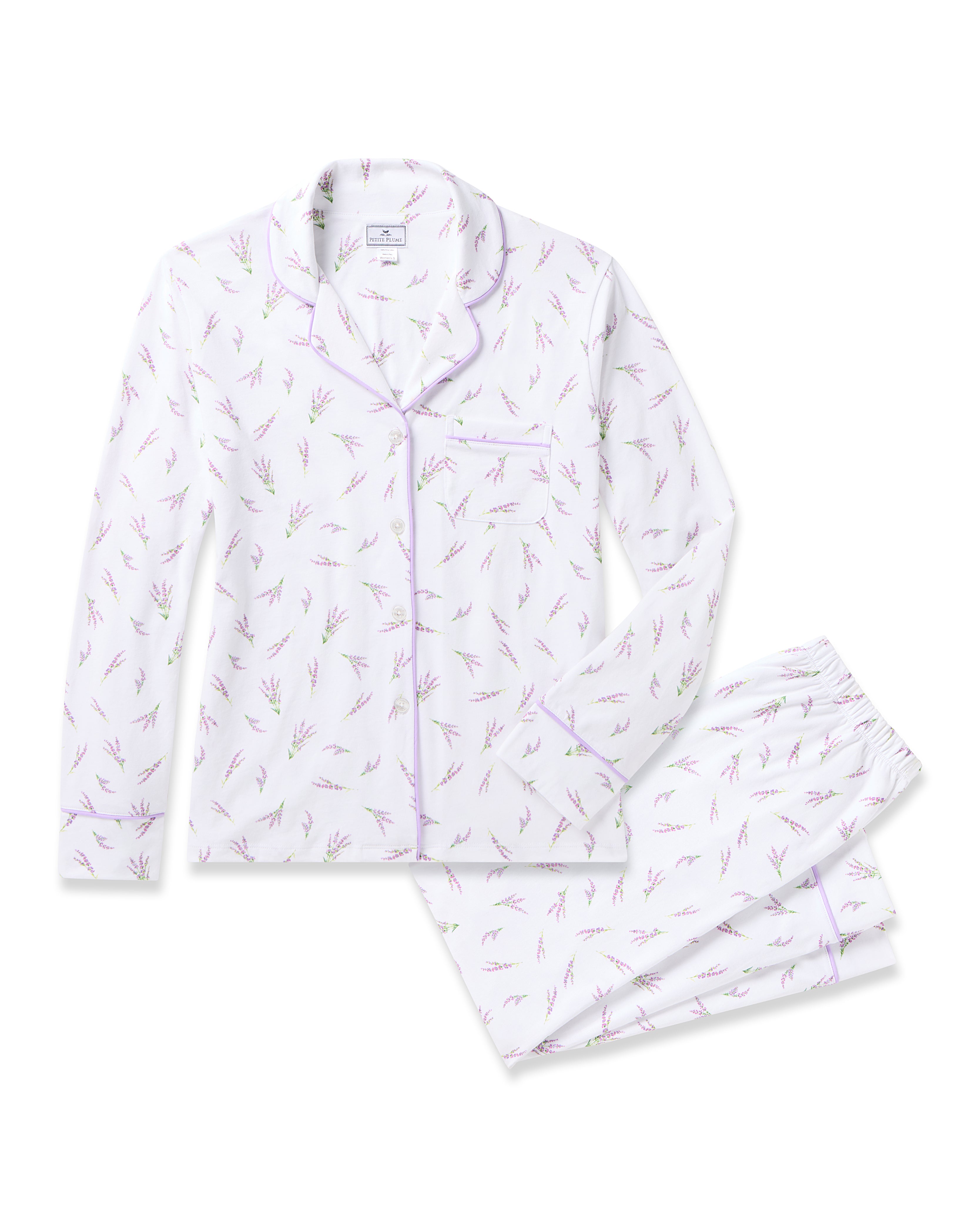 Petite Plumes Womens Pima Pajama Set in Fields of Provence boasts a timeless silhouette with light purple floral patterns. The set includes a long-sleeve top with a collar, front pocket, and button-down closure, while the matching pants feature an elastic waistband, all elegantly displayed on a white background.