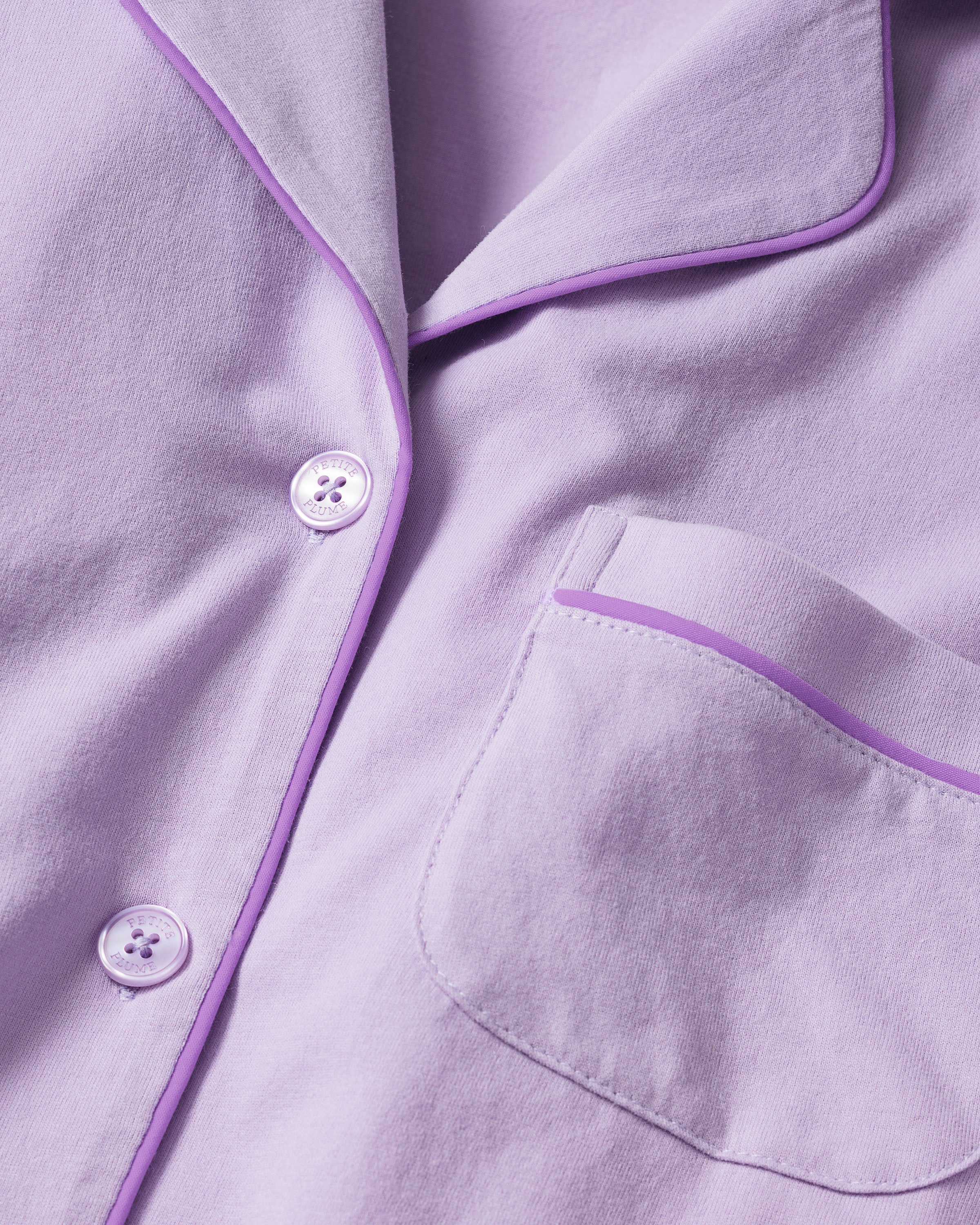 Close-up of the Womens Pima Pajama Set in Lavender by Petite Plume, crafted from Peruvian Pima cotton. The top features lavender buttons, a left-side pocket with darker purple piping, and a soft texture that epitomizes luxury sleepwear.