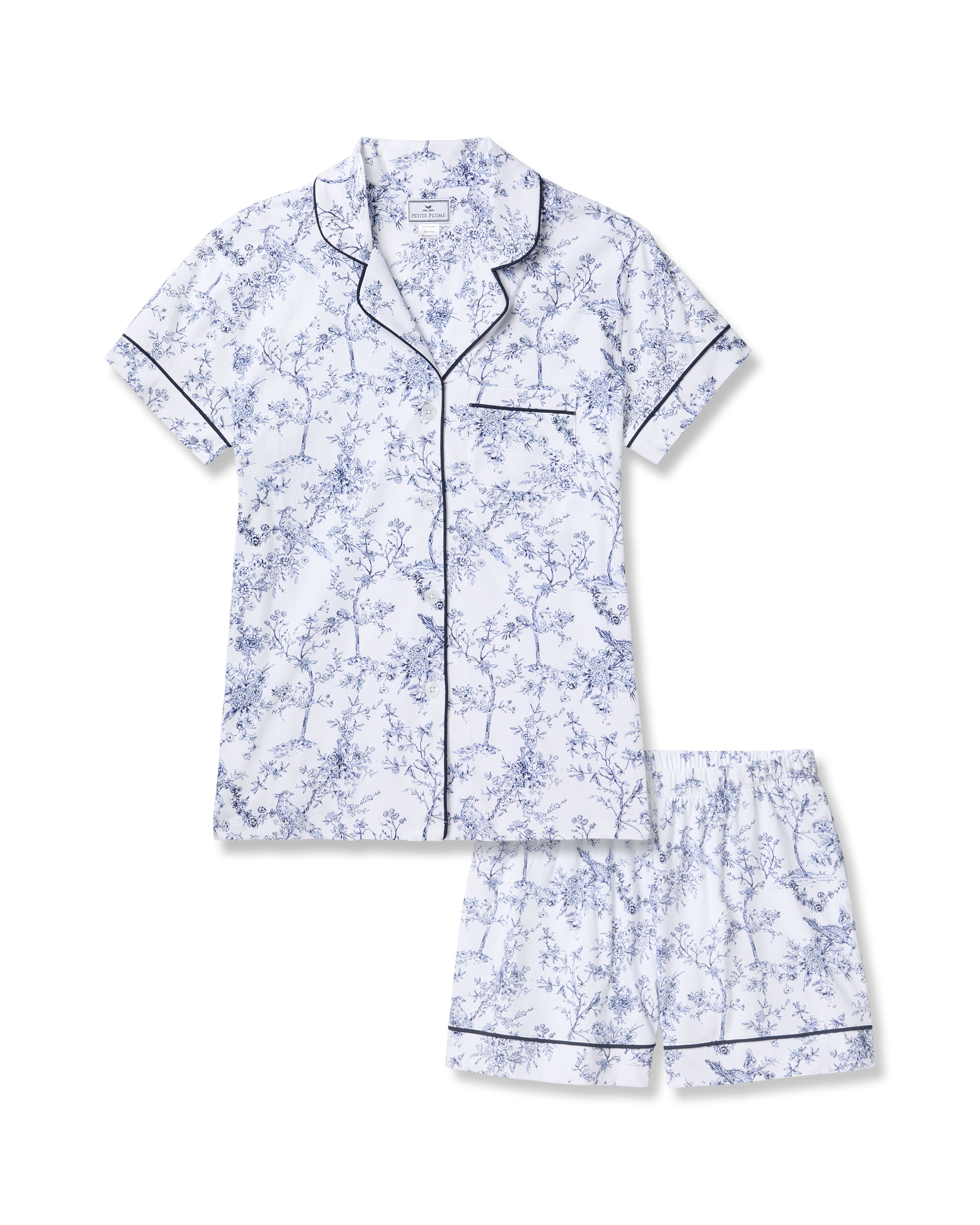 Experience botanical elegance with the Womens Pima Short Sleeve Short Set in Timeless Toile by Petite Plume. This luxurious pajama set features a white fabric adorned with a blue floral print, plus black piping trim on the collar, sleeves, and pocket for classic charm.