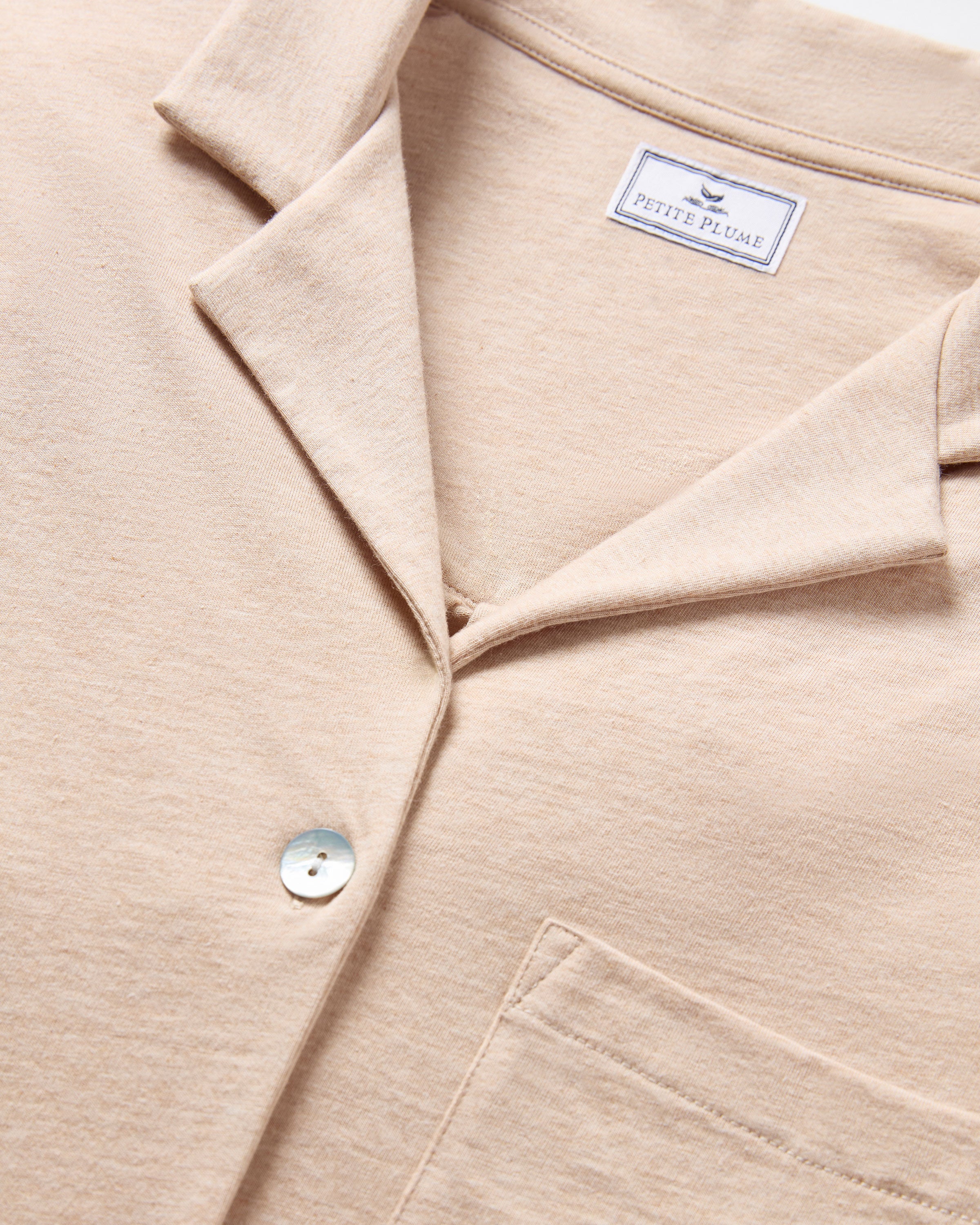 Close-up of a camel, collared shirt from The Olivia Wide Leg Pima Pajama Set, made of luxurious Peruvian Pima cotton by Petite Plume. It features a buttoned front and single chest pocket, with soft textured fabric embodying elegance and comfort.