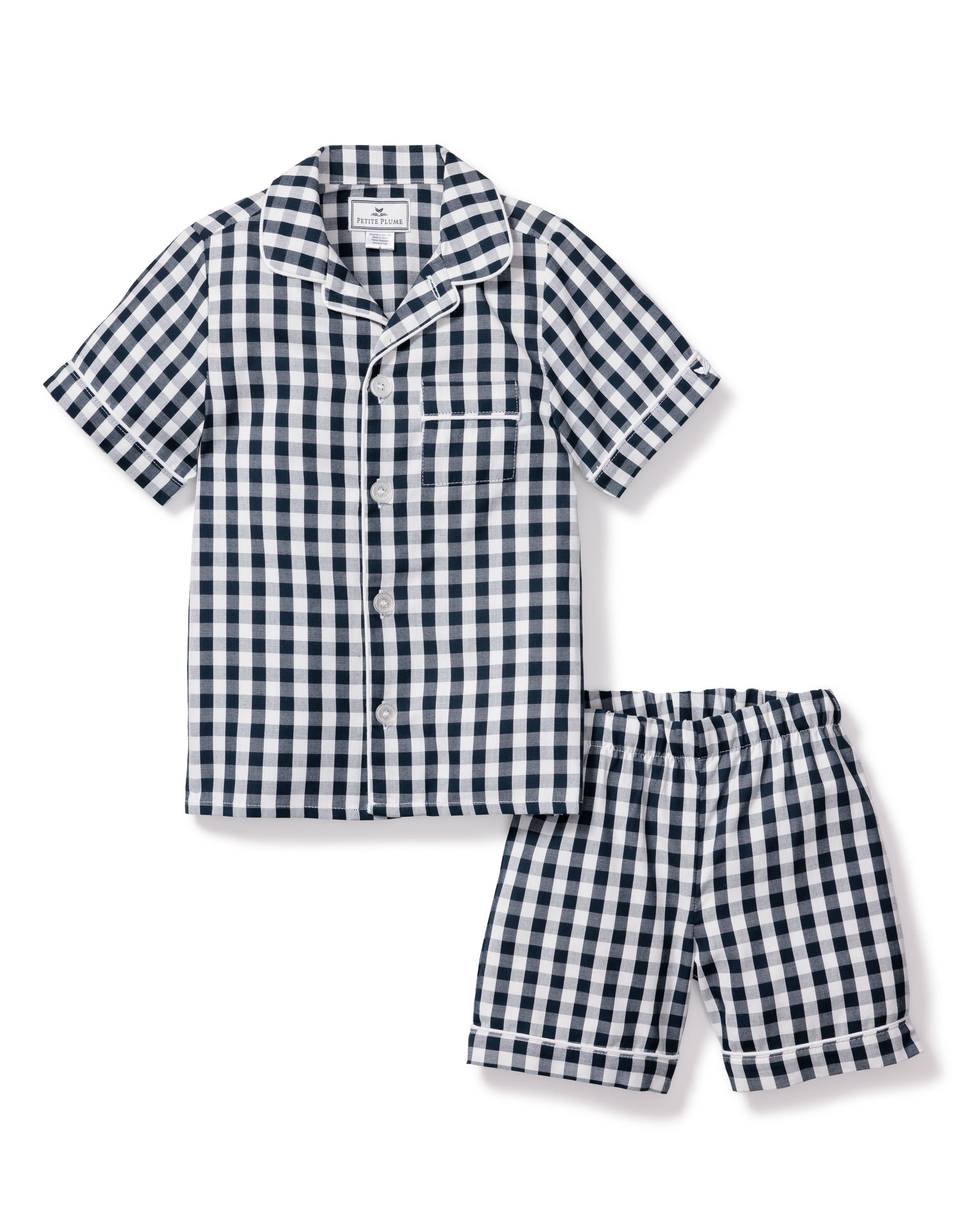 The Kids Pajama Short Set in Navy Gingham by Petite Plume is made from yarn-dyed cotton, featuring a button-down top with a chest pocket and shorts with an elastic waistband for comfort.