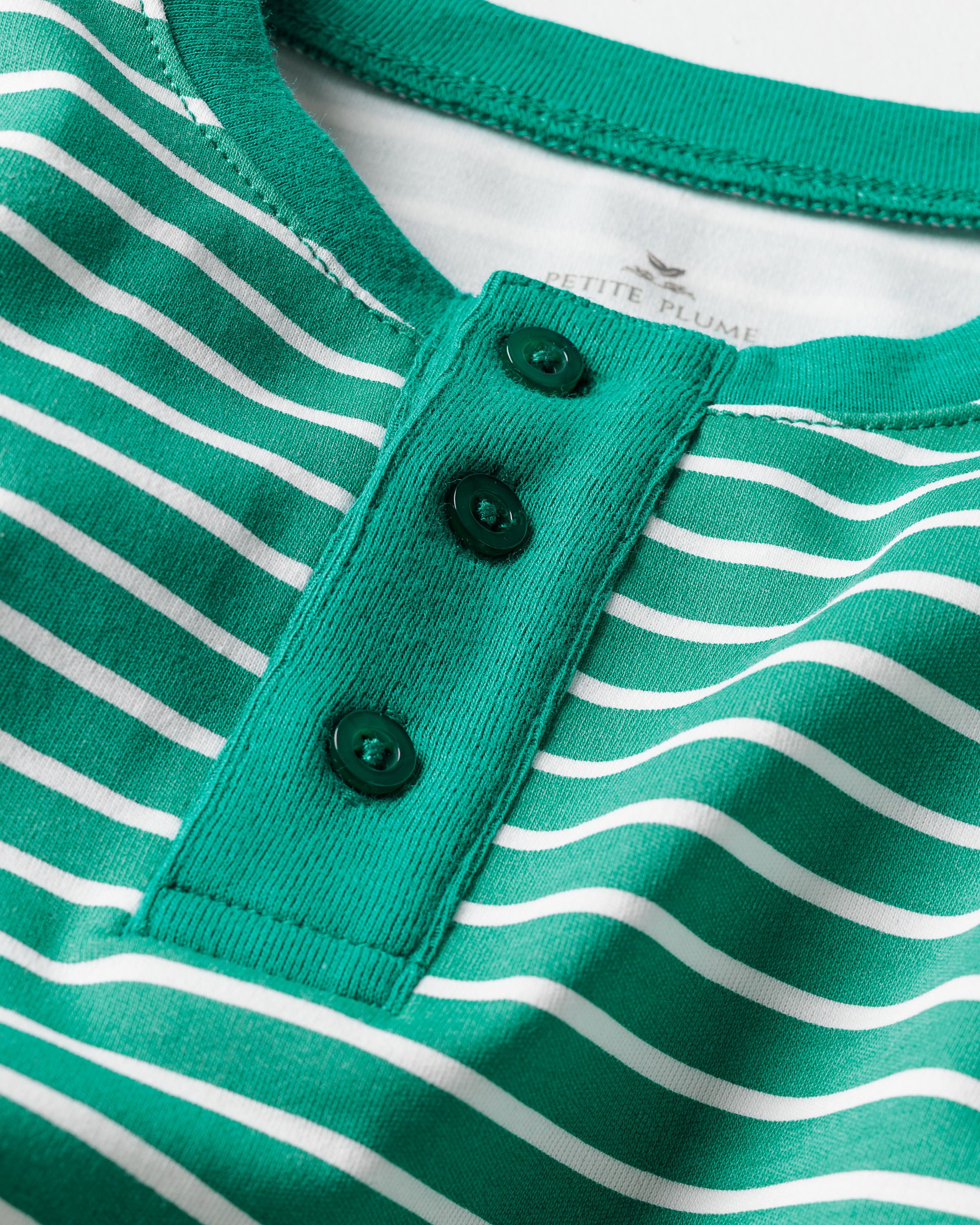 Close-up of a Kids Pima Snug Fit Pajama Set in Green Stripe by Petite Plume, featuring a green and white striped long sleeve top with three dark green buttons on the placket, crafted from soft Pima cotton.