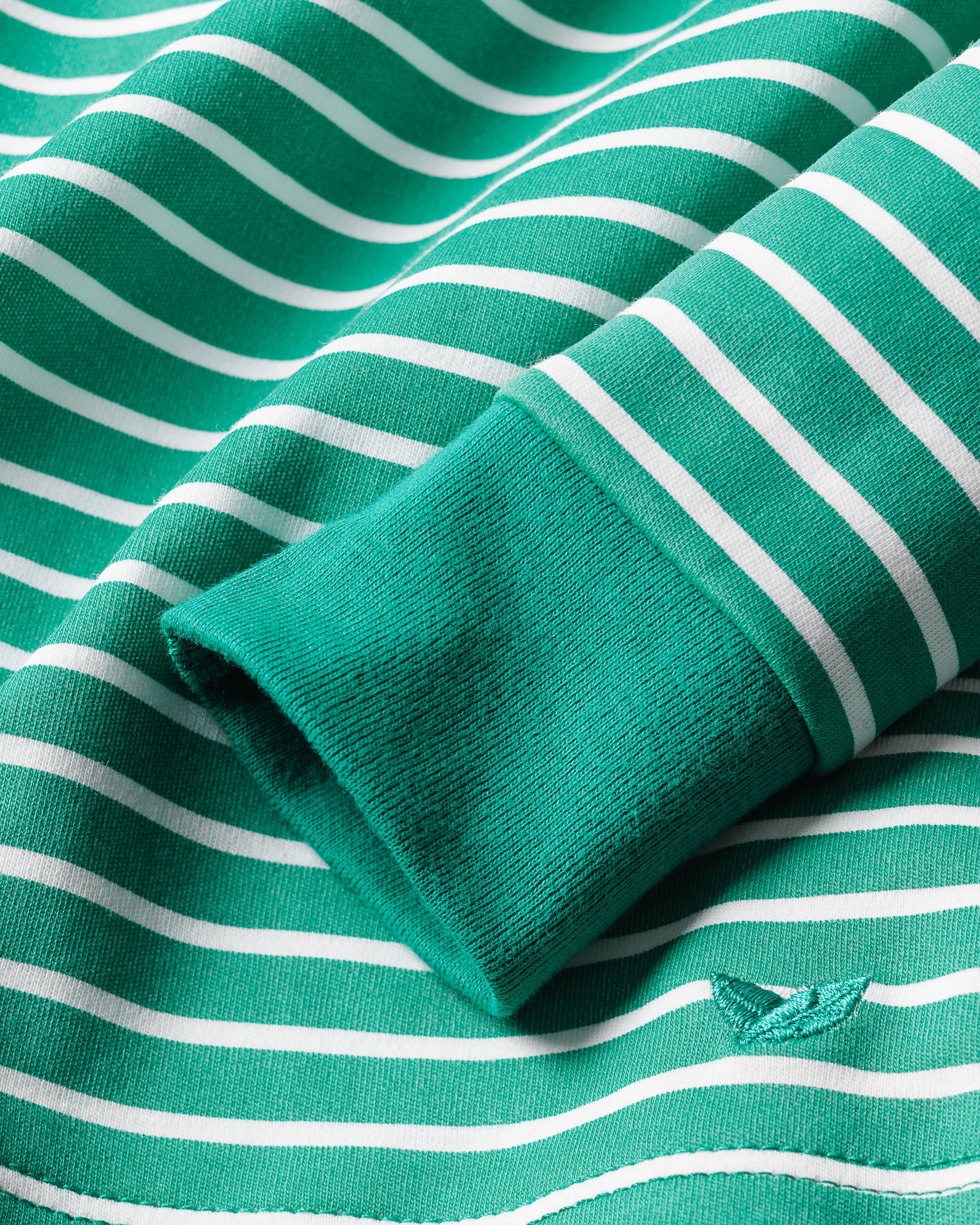 Close-up of Kids Pima Snug Fit Pajama Set in Green Stripe by Petite Plume, showing a neatly folded sleeve. The soft Pima cotton has white horizontal stripes and a subtle embroidery near the edge.