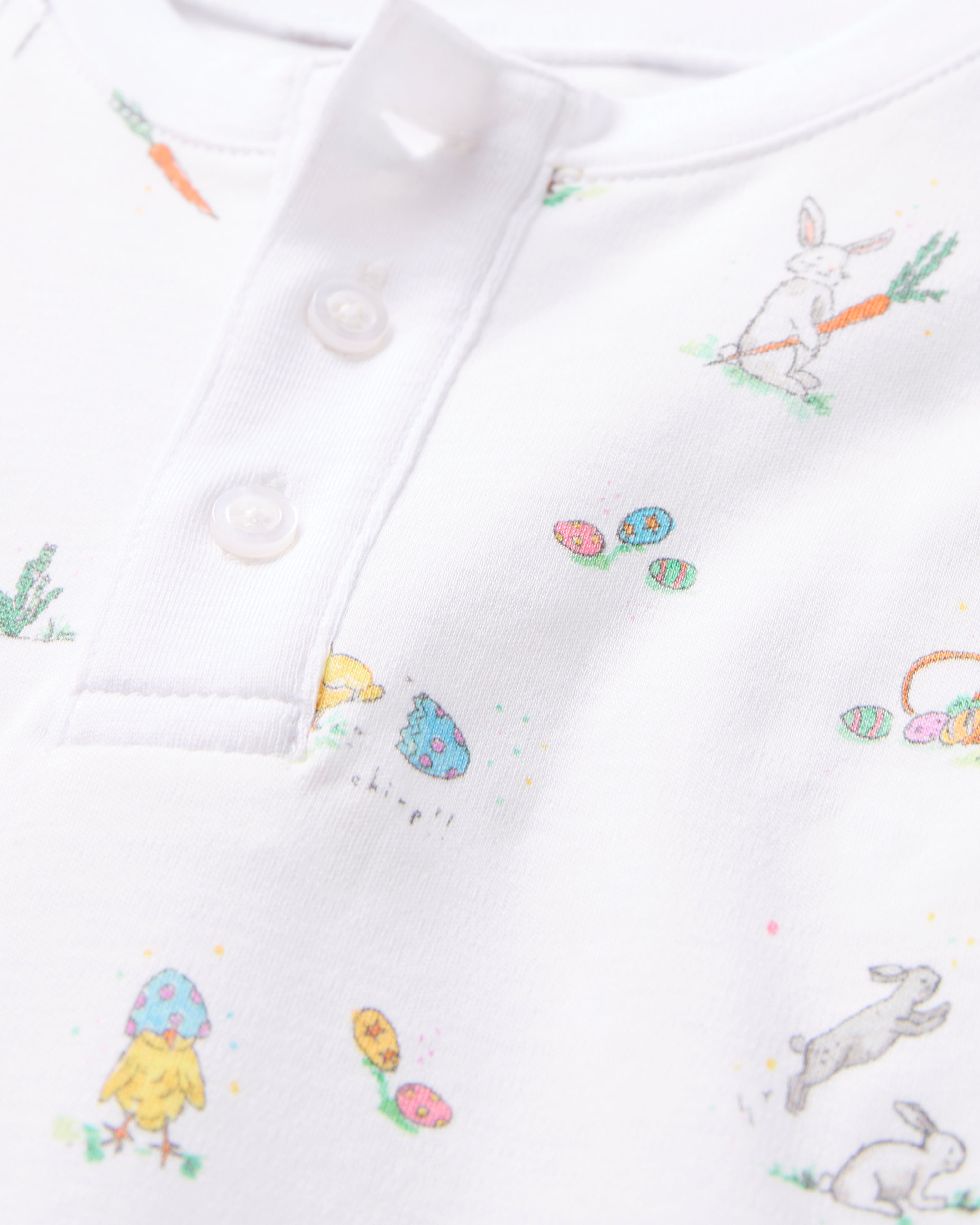 Close-up of Petite Plumes Kids Pima Snug Fit Pajama Set in Easter Frolic, featuring small printed designs. It includes a rabbit with a carrot, colorful Easter eggs, and a chick with a blue eggshell; buttoned collar with two buttons, perfect for coordinated style enthusiasts.