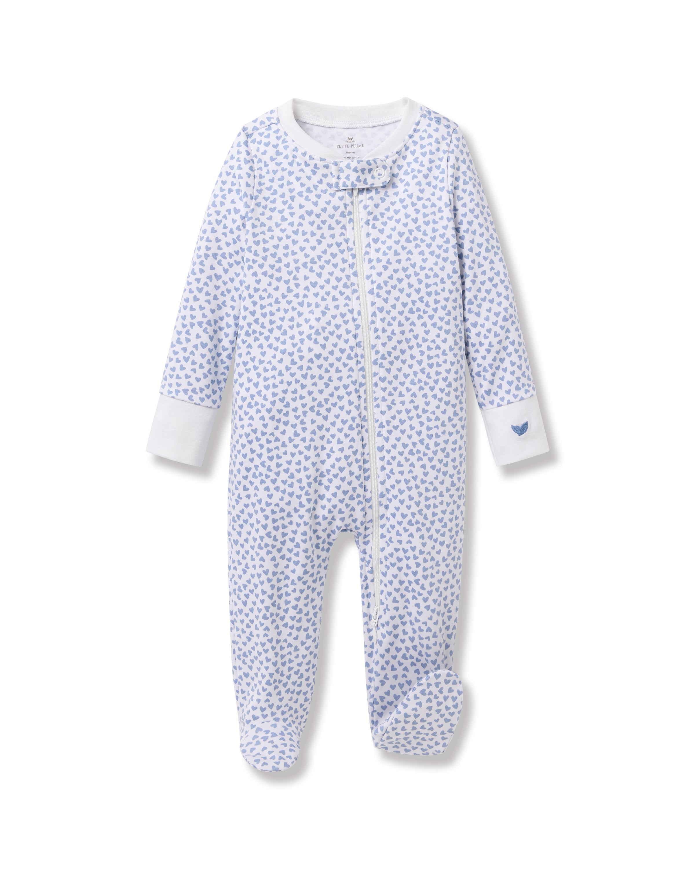 The Babys Pima Romper in Bluehearts by Petite Plume features a snug fit with a blue hearts design on white Pima cotton, a diagonal neck-to-leg zipper, and white wrist cuffs, all showcased against a plain backdrop.