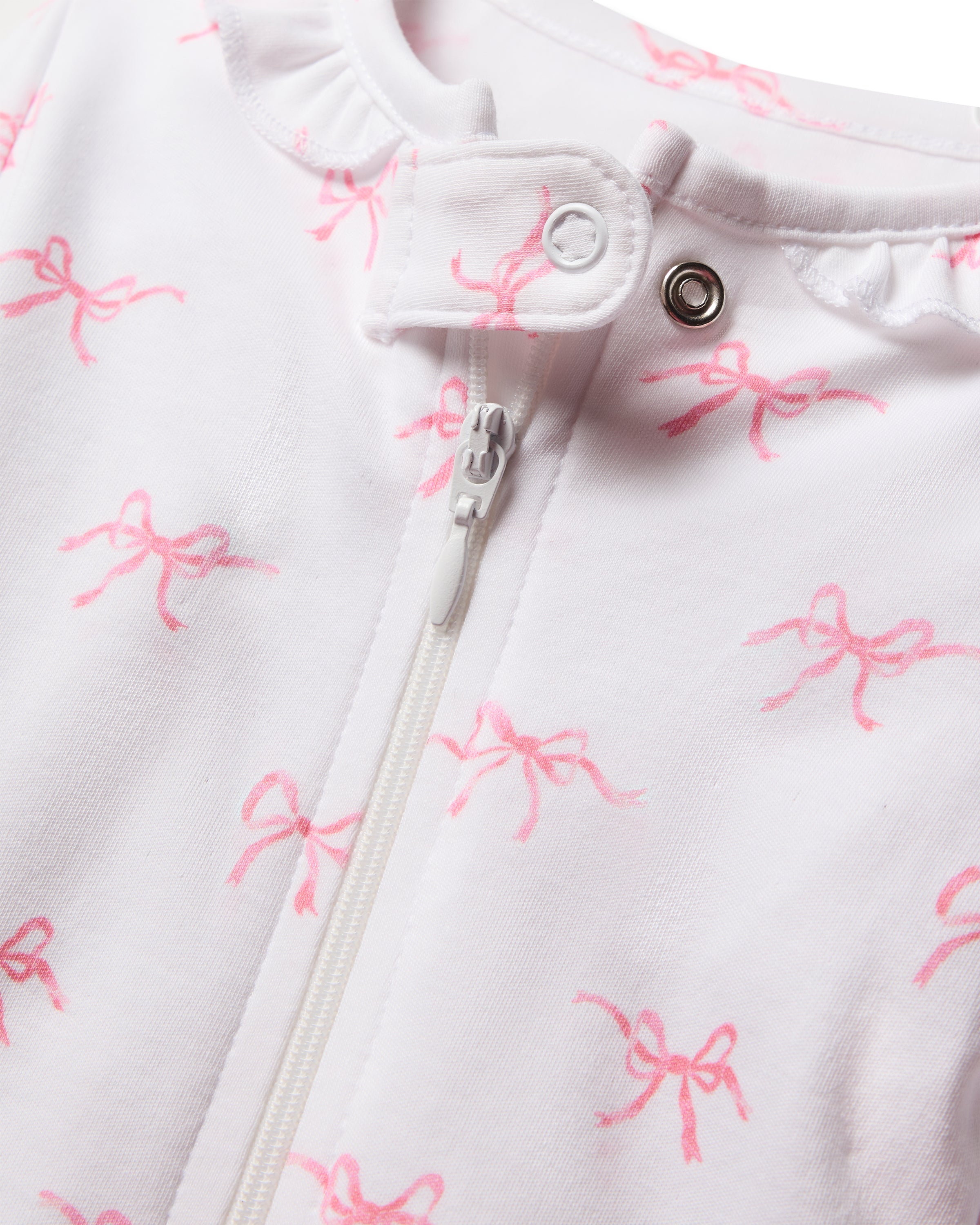 Close-up of Petite Plumes Babys Pima Ruffle Collar Romper in Blushing Bows, showcasing white fabric with a zipper and snap button, adorned with vibrant hues and small pink bows. Made from 100% Pima cotton, this charming piece is perfect for Valentines Day.