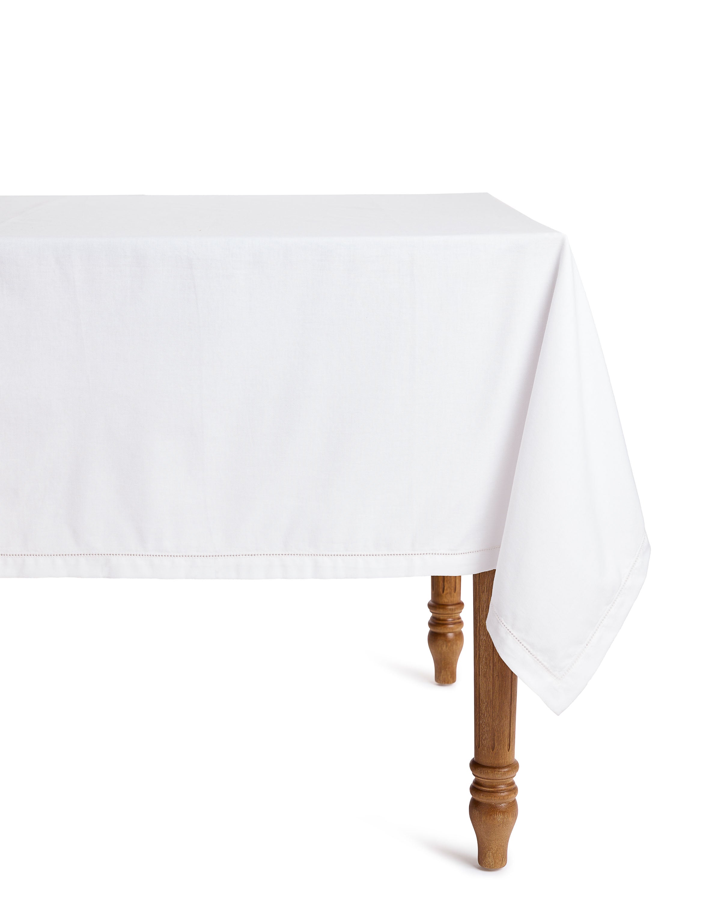 The Signature Twill Table Linen Set in Vintage French Stripe by Petite Plume elegantly drapes over a wooden table with ornate legs against a plain background, hanging gracefully on the right side. Its design is simple yet sophisticated, ideal for creating a festive tablescape.