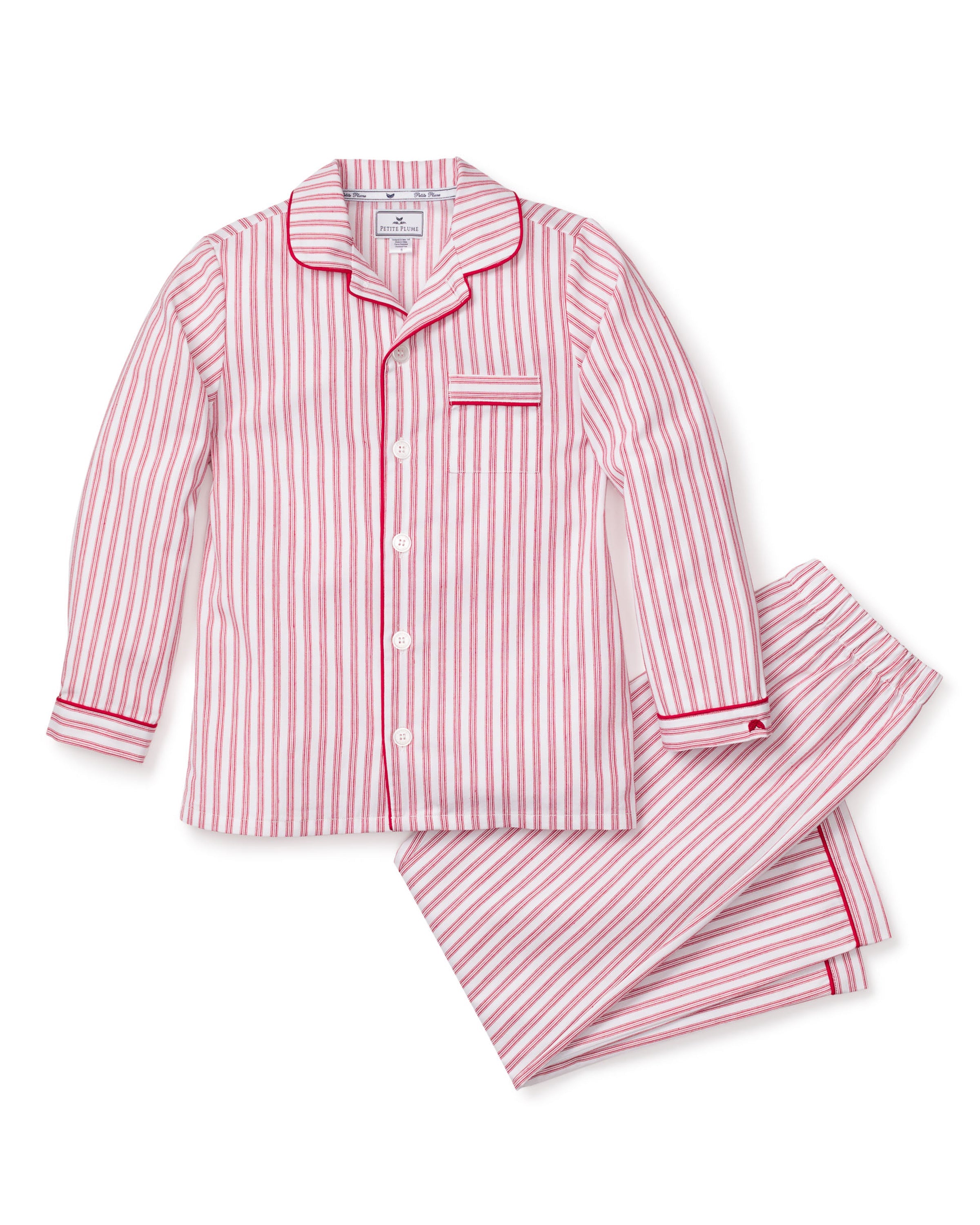 The Kids Twill Pajama Set in Antique Red Ticking by Petite Plume features a yarn-dyed cotton button-up top with vertical pink and white stripes, red piping on the collar and chest pocket, paired with matching pants for cozy evenings.