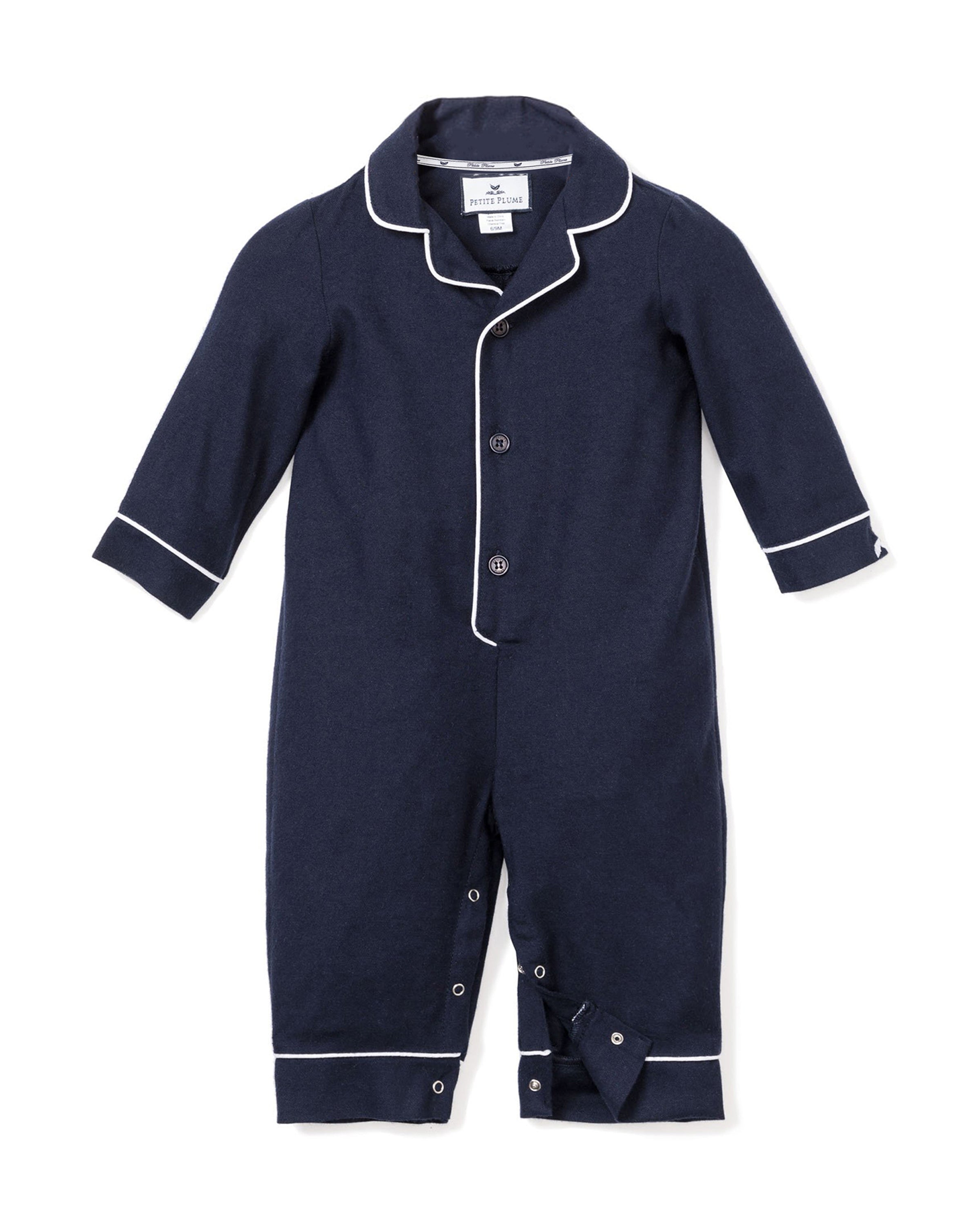 The Petite Plume Babys Flannel Romper in Navy with White Piping offers a soft and comfortable sleepwear option. It features a button-down front and snap buttons at the legs, along with white piping on the collar, cuffs, and hems for easy fastening and style.