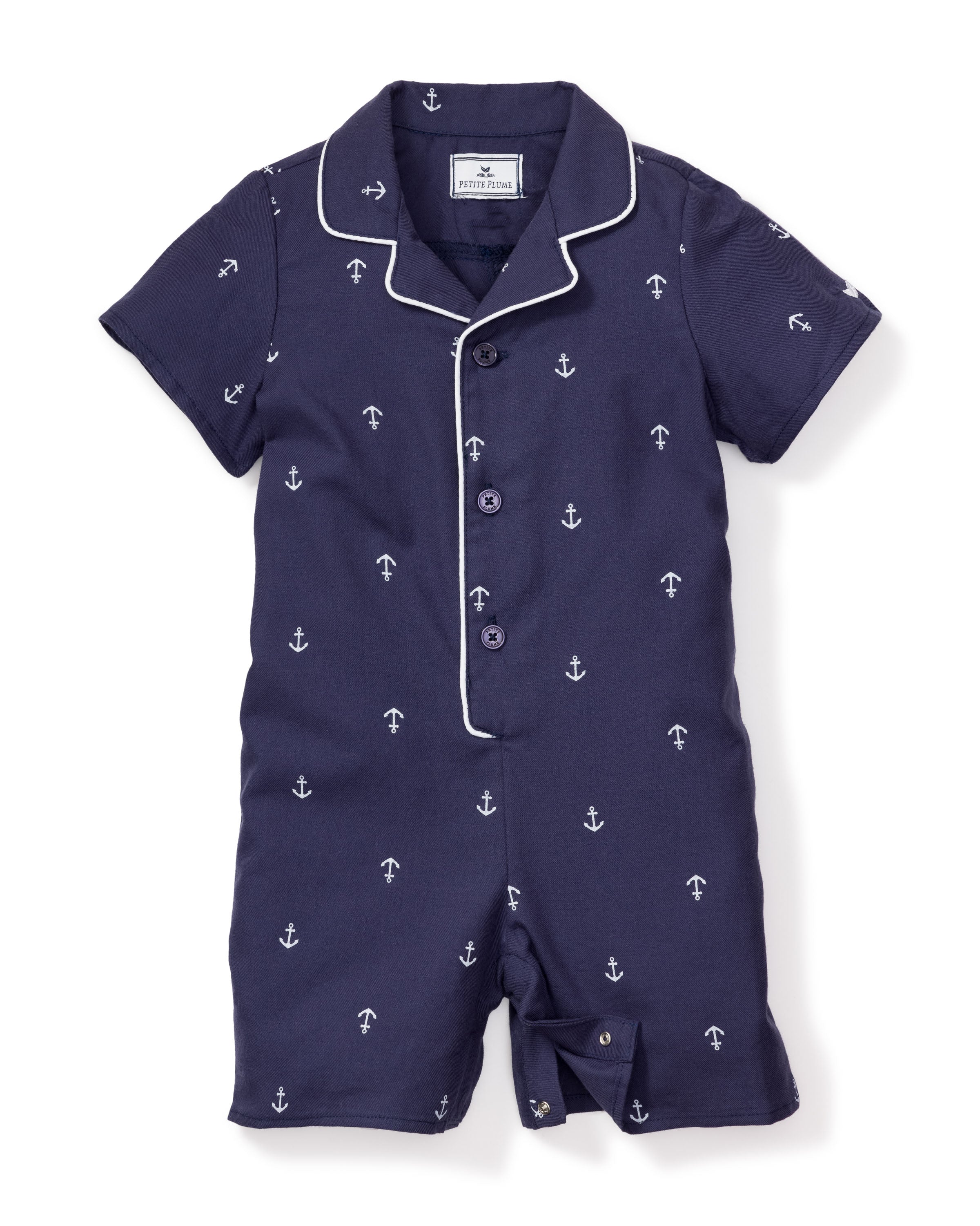 Petite Plumes Babys Twill Summer Romper in Portsmouth Anchors is a navy blue infant onesie made from soft yarn-dyed cotton, showcasing short sleeves, buttons, white piping on the collar and buttons, and a delightful navy anchor and arrow pattern throughout.