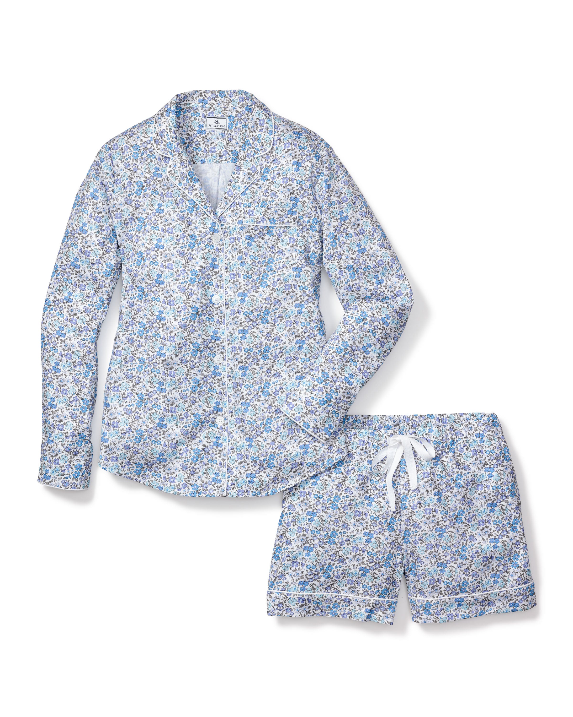 The Womens Twill Pajama Long Sleeve Short Set in Fleur DAzur by Petite Plume boasts a vintage-inspired blue and white floral print. The top features pearl buttons, a left chest pocket, and white piping, while the shorts come with a white drawstring for an elegant touch.