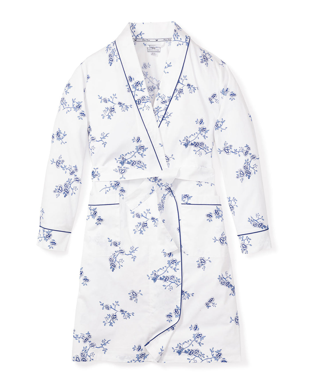 The Womens Twill Robe in Indigo Floral by Petite Plume is crafted from high-quality cotton. It features a white floral design with blue flowers, long sleeves, a belted waist, and navy piping on the collar, cuffs, and pockets. The vintage print enhances its charm for cozy loungewear.