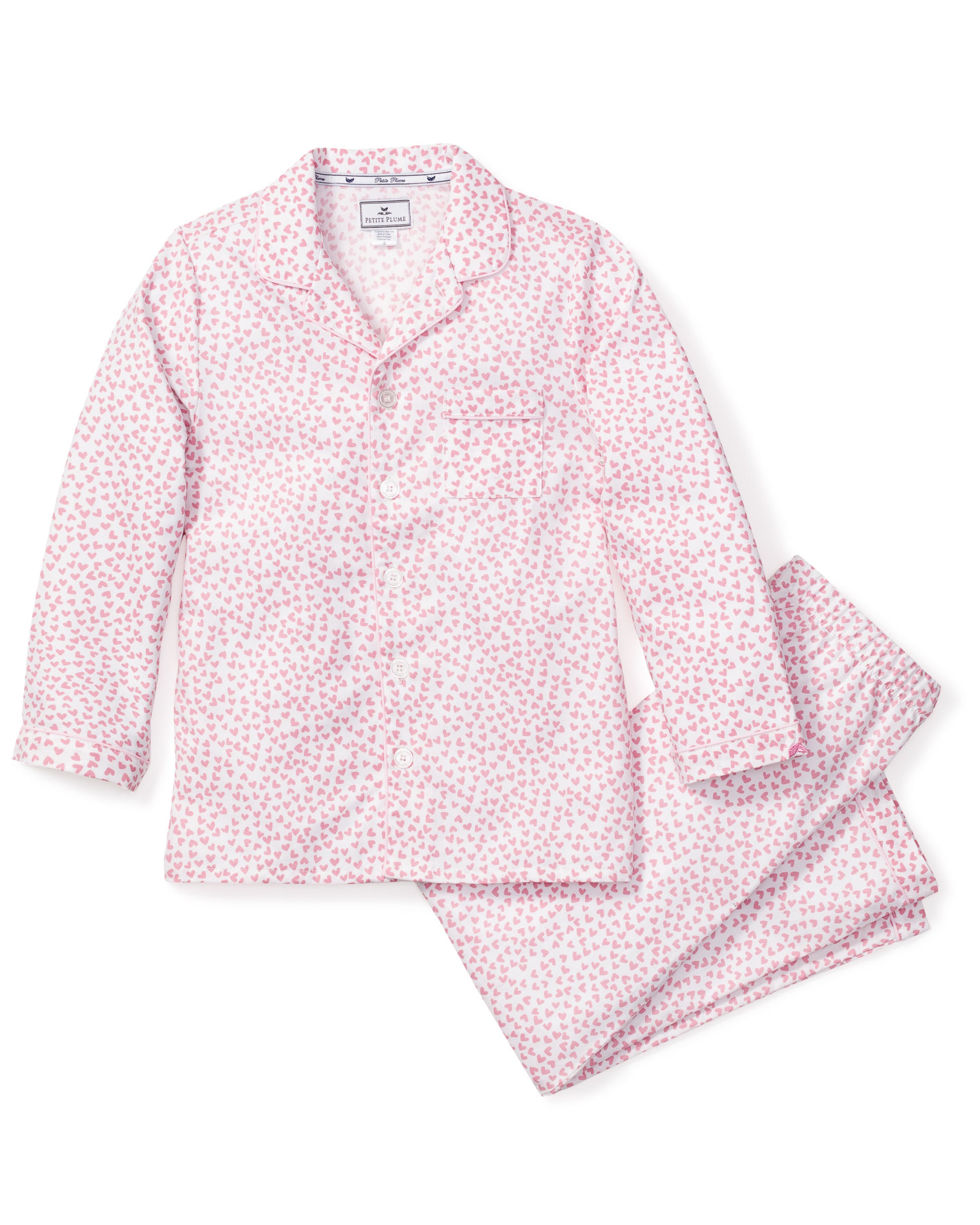 The Kids Twill Pajama Set in Sweethearts by Petite Plume features a pink and white floral pattern with a button-up top and matching pants, crafted from light fabric for a luxurious, cozy experience.